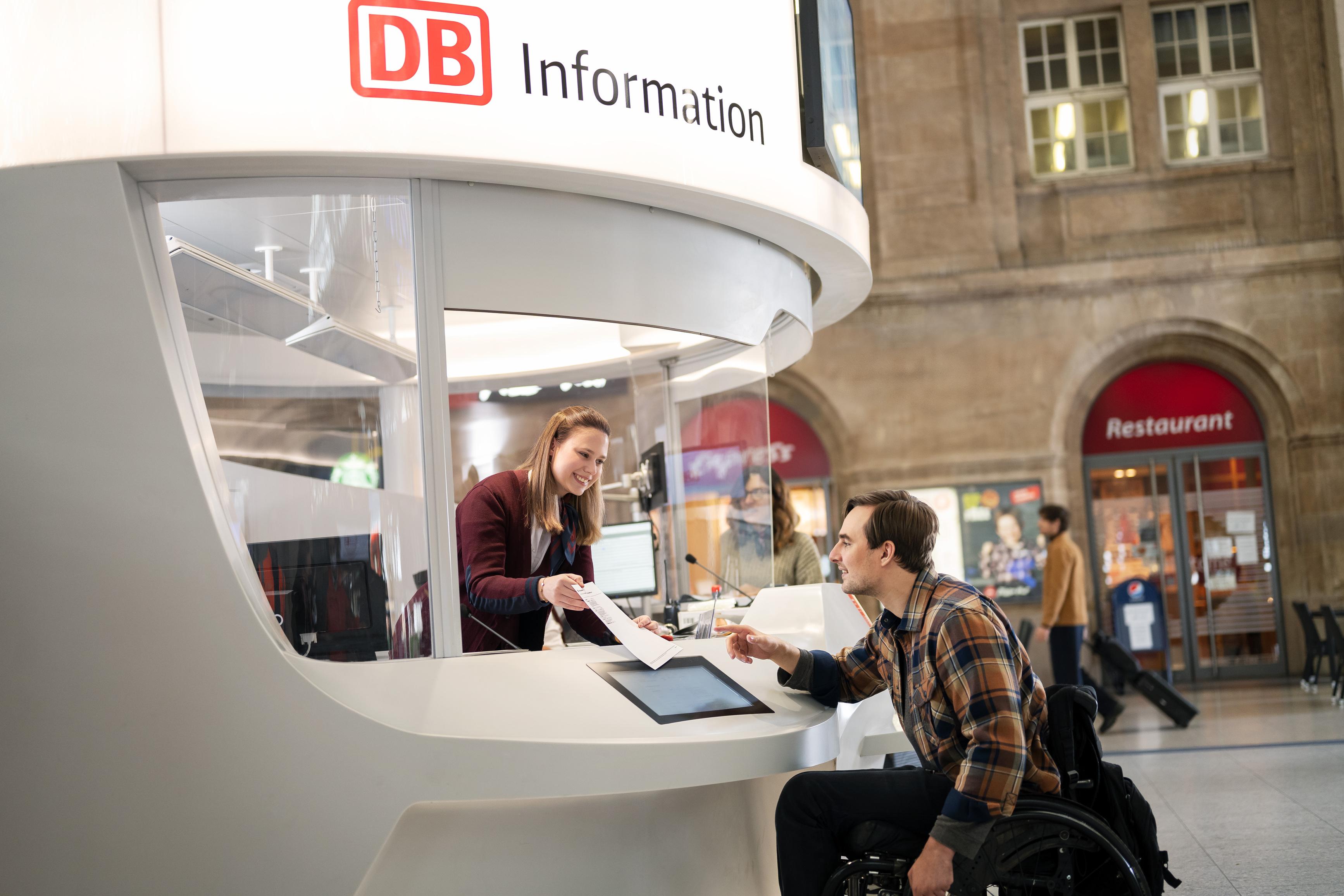 Ein Rollstuhlfahrer informiert sich an einer DB Information im Bahnhof.