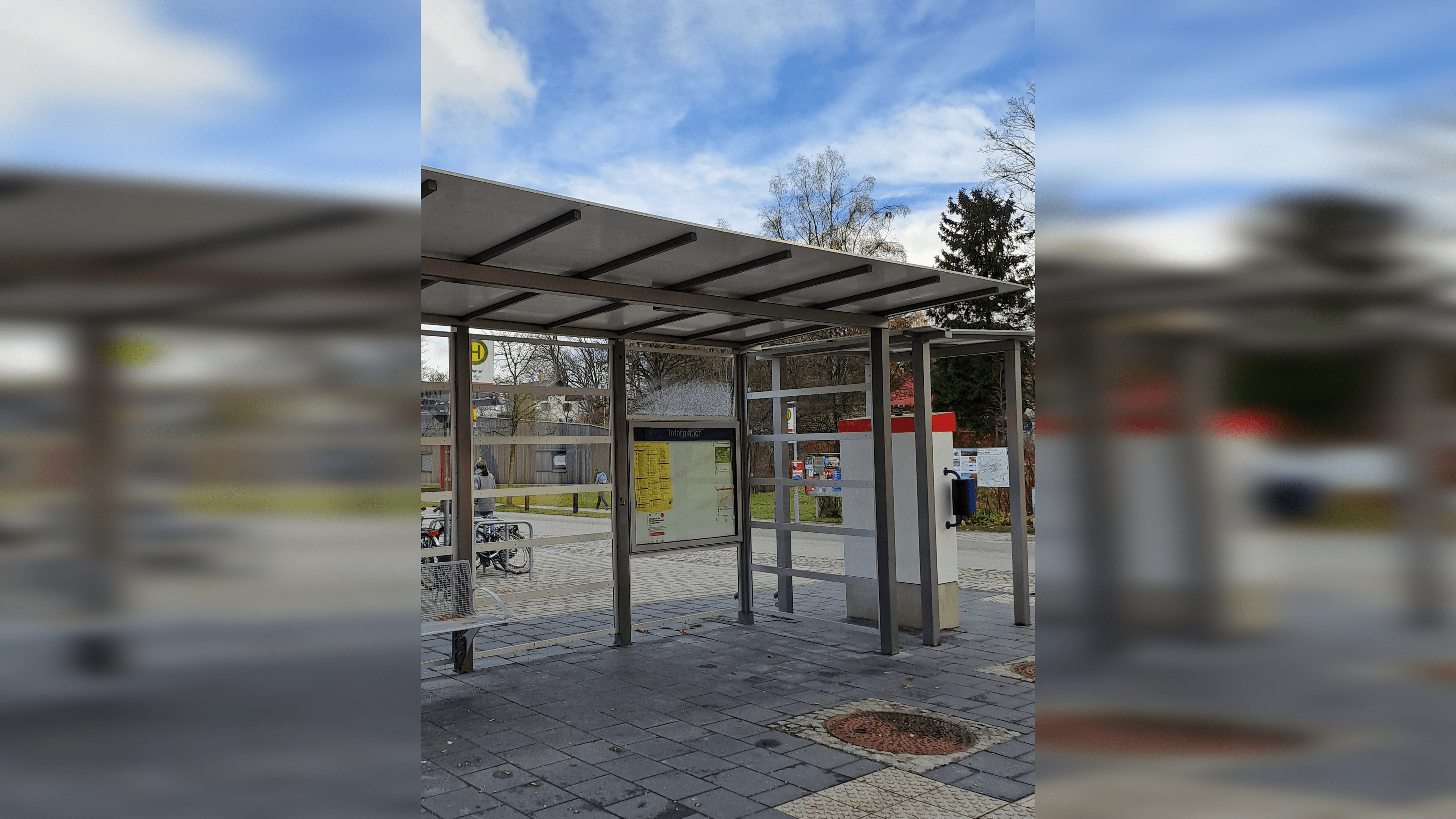 Abgebildet ein Wetterschutzhaus mit transparenten Paneelen. Im Hintergrund eine Fahrradabstellanlage.