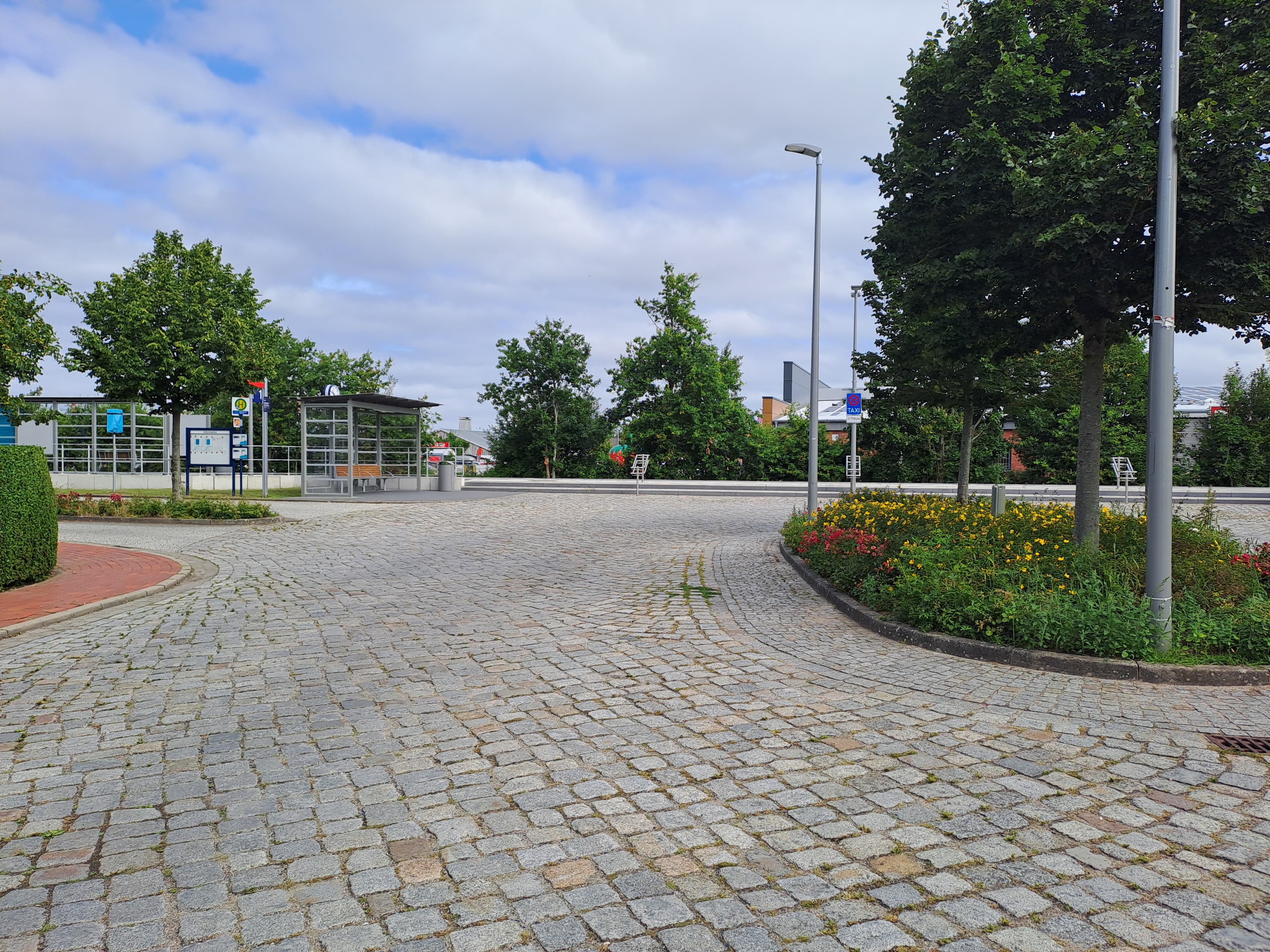 Der gepflasterte Vorplatz des Bahnhofs nebst Blumenrabatten.