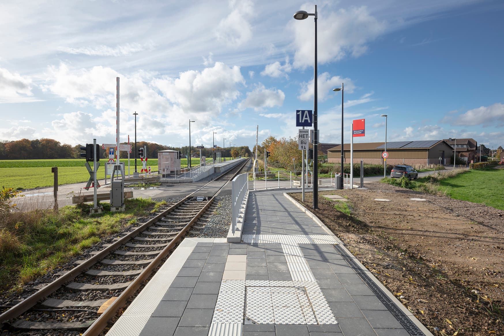 Die Rampe vom Bahnsteig aus betrachtet mit Geländer und Lampen. Ein taktile Leitsystem ist auf dem Bahnsteig.