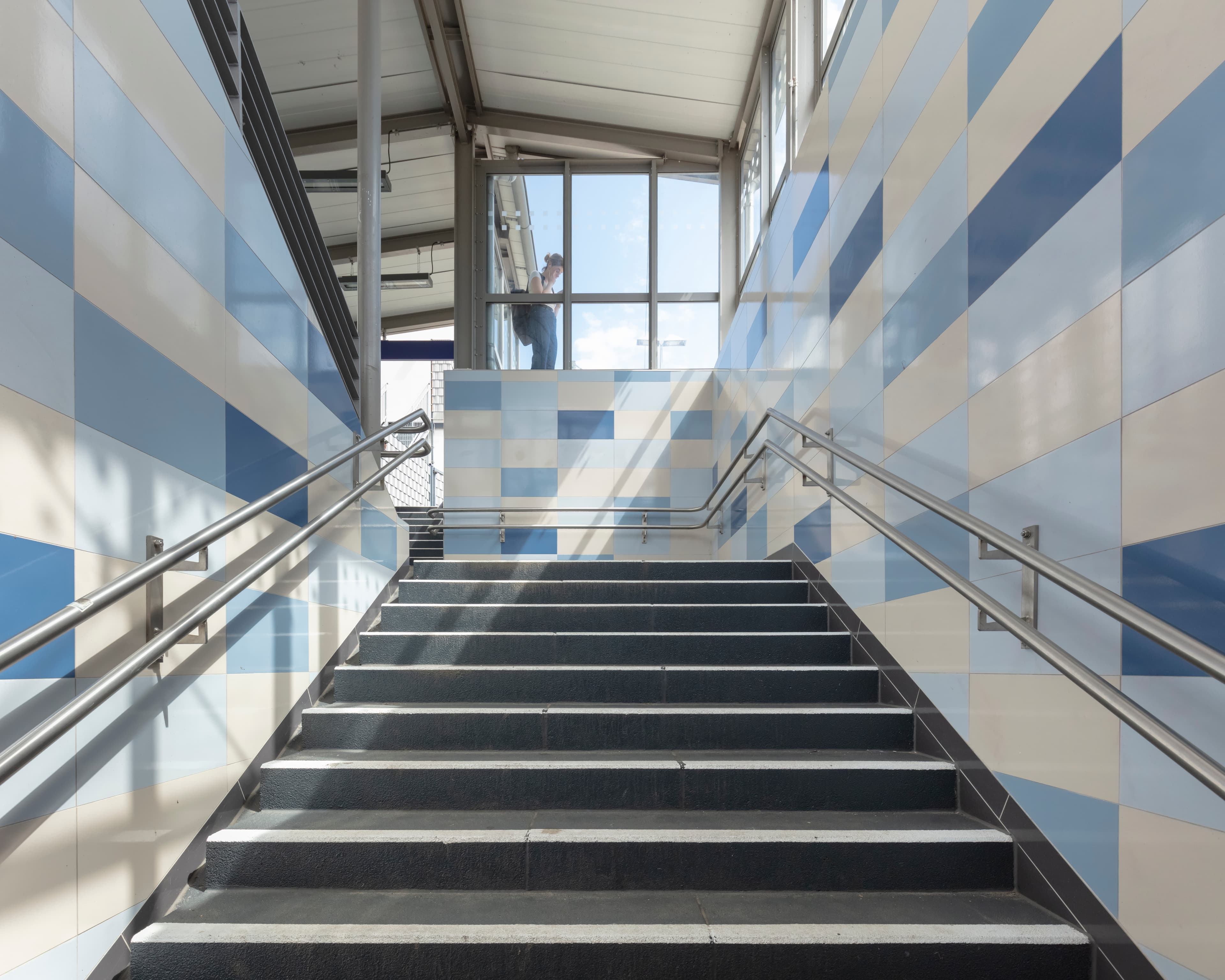 Treppenaufgang zum Bahnsteig mit neu gestalteten Wänden.