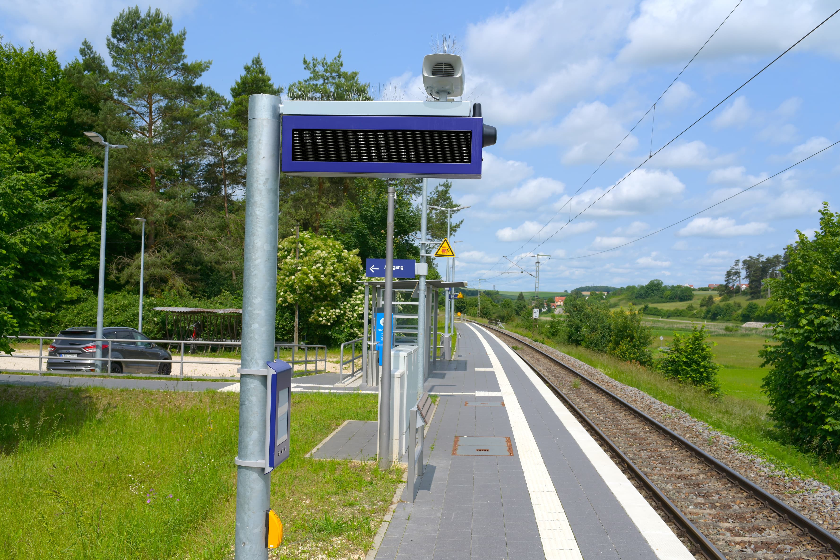 Links im Bild der Mast des DSA+. Daran ein Taster für die Audiodruchsagen. Darüber der digitale Aushang Bau und der zweizeilige DSA+.