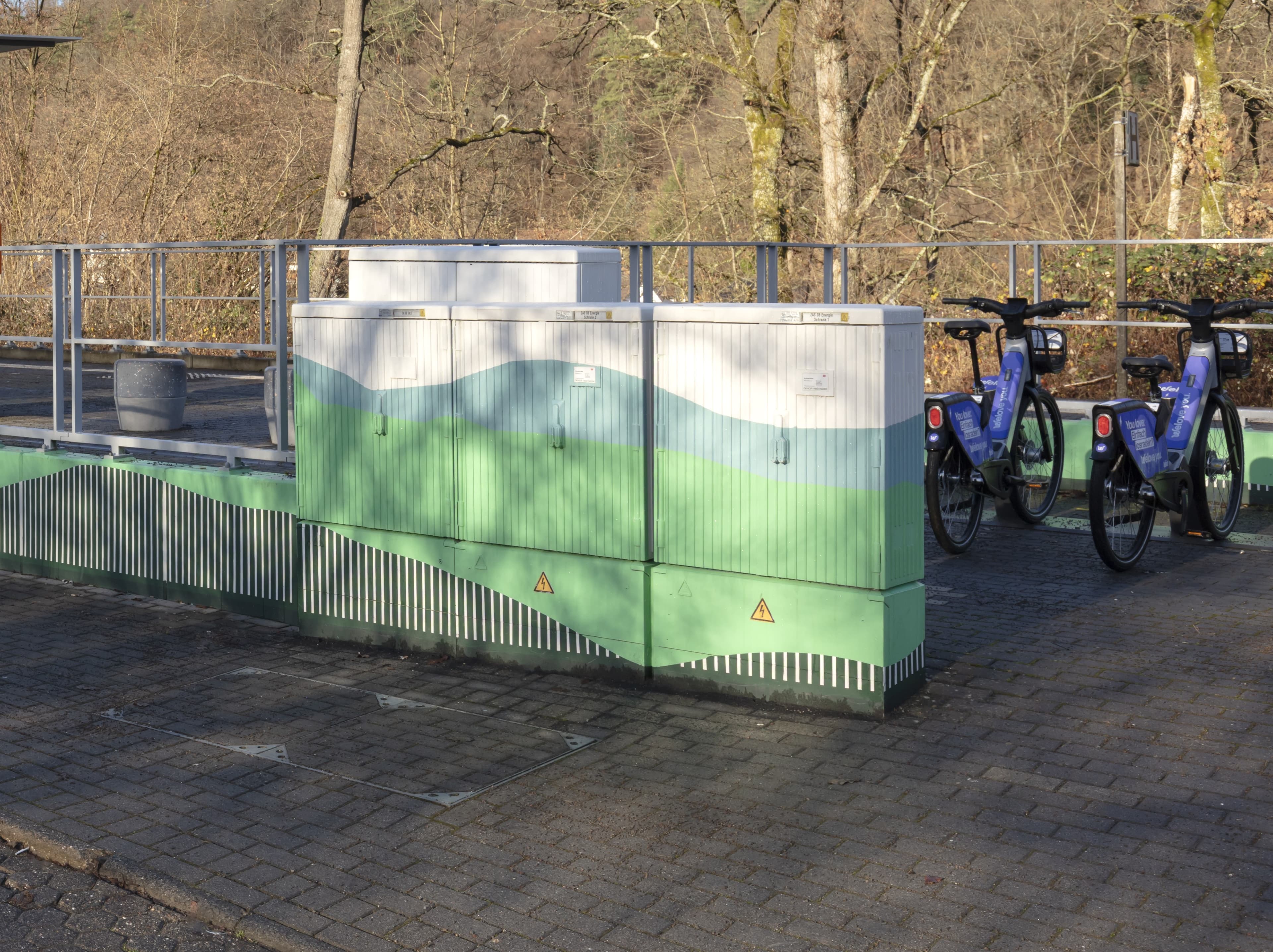 Blick auf neugestaltete Verteilerkästen. Im Hintergrund zwei Fahrräder.