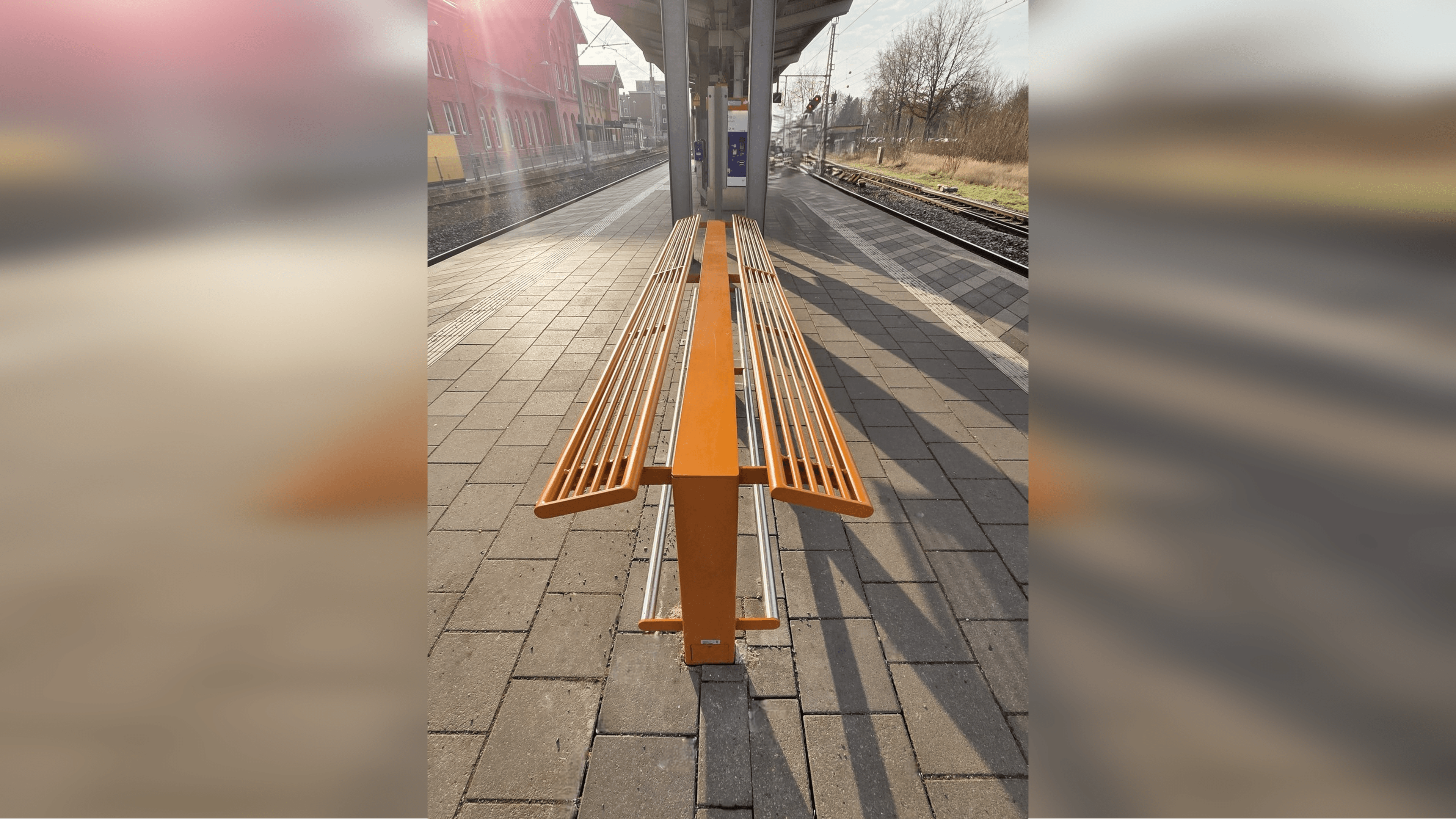 Ein orangner Anlehner auf einem Bahnsteig.