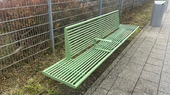 Blick auf eine grüne Bank auf dem Bahnsteig