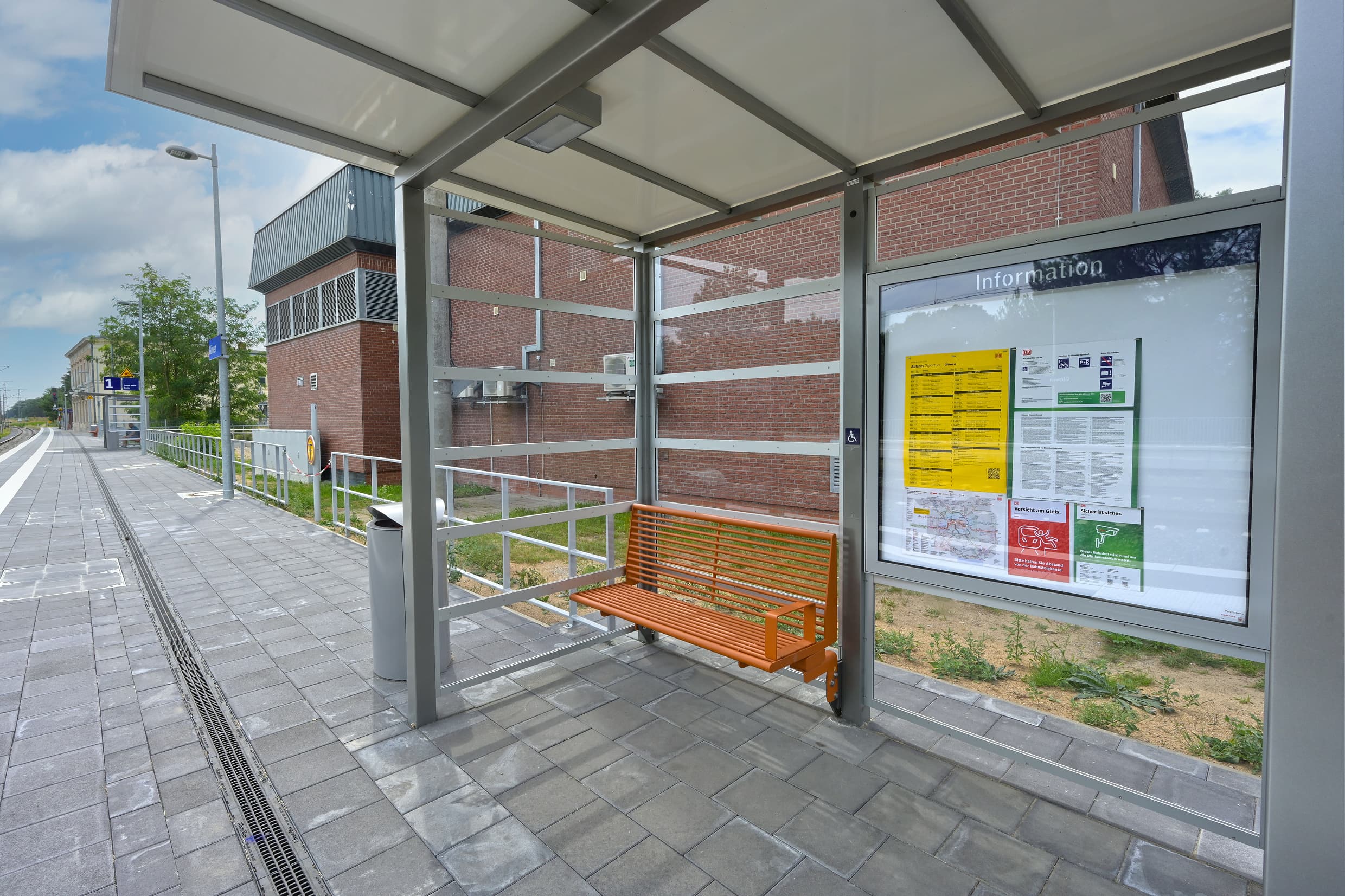 Modernisiertes Wetterschutzhäuschen mit Sitzbank am Bahnsteig.