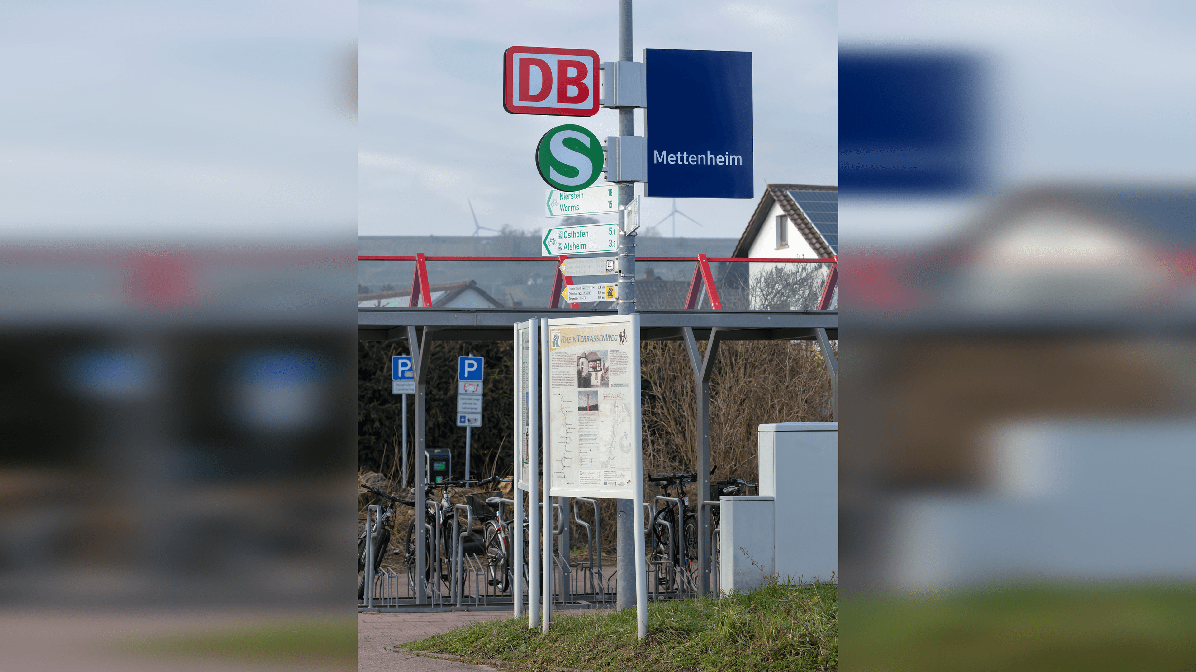 Bahnhofsschild mit DB Logo und S-Bahn Logo an einer Stele. Darunter eine Infotafel.