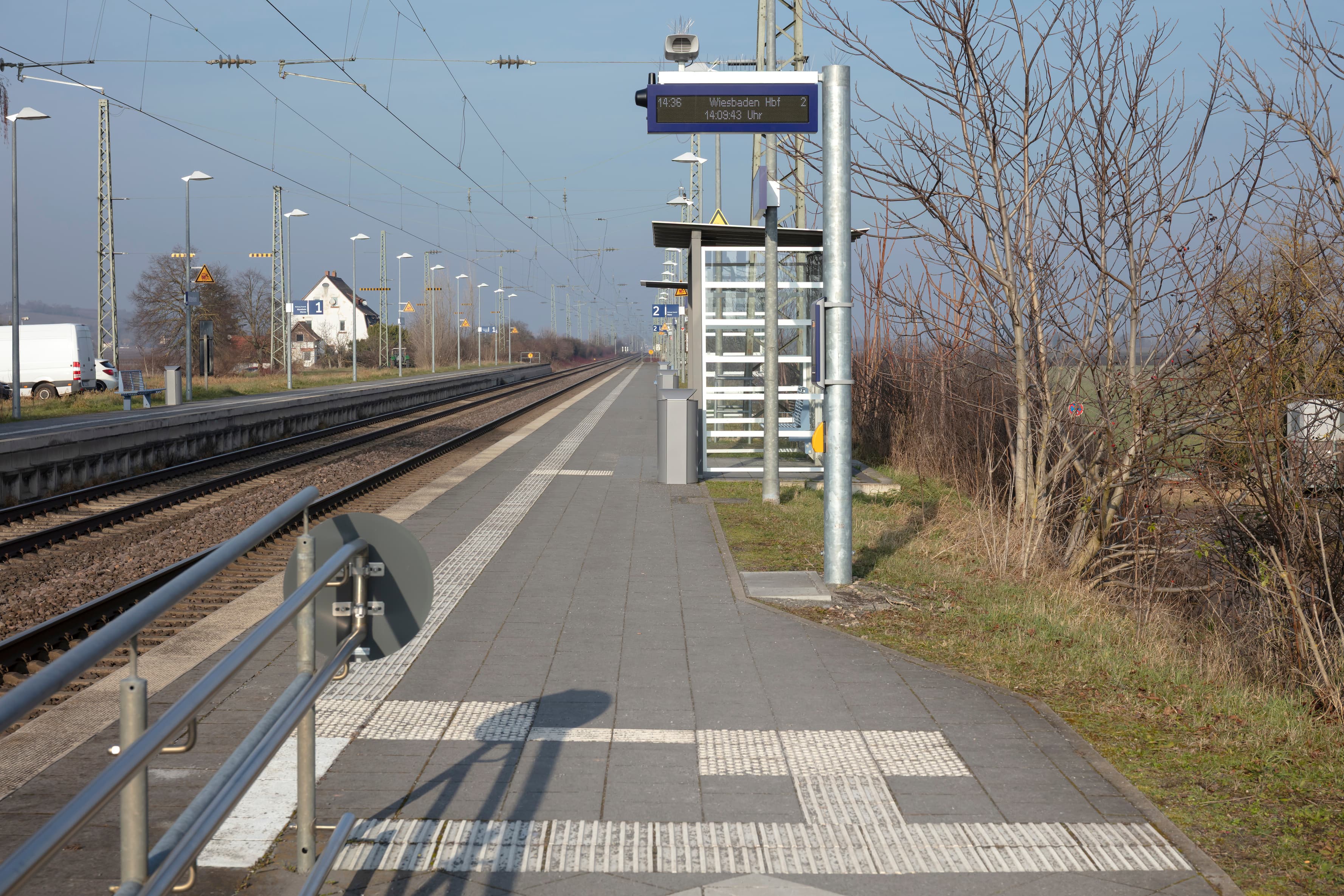 Der dynamische Schriftenanzeiger am Beginn des Bahnsteiges. Links der Handlauf der Zuwegung auf dem Boden das Blindenleitsystem.