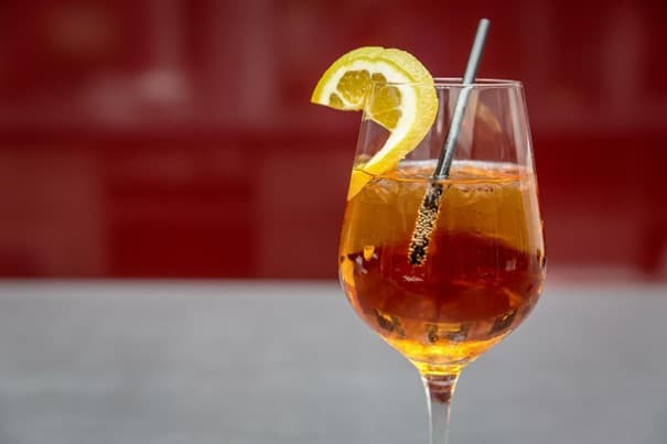 Ein mit Aperol-Spritz und Eiswürfeln gefülltes Weinglas.