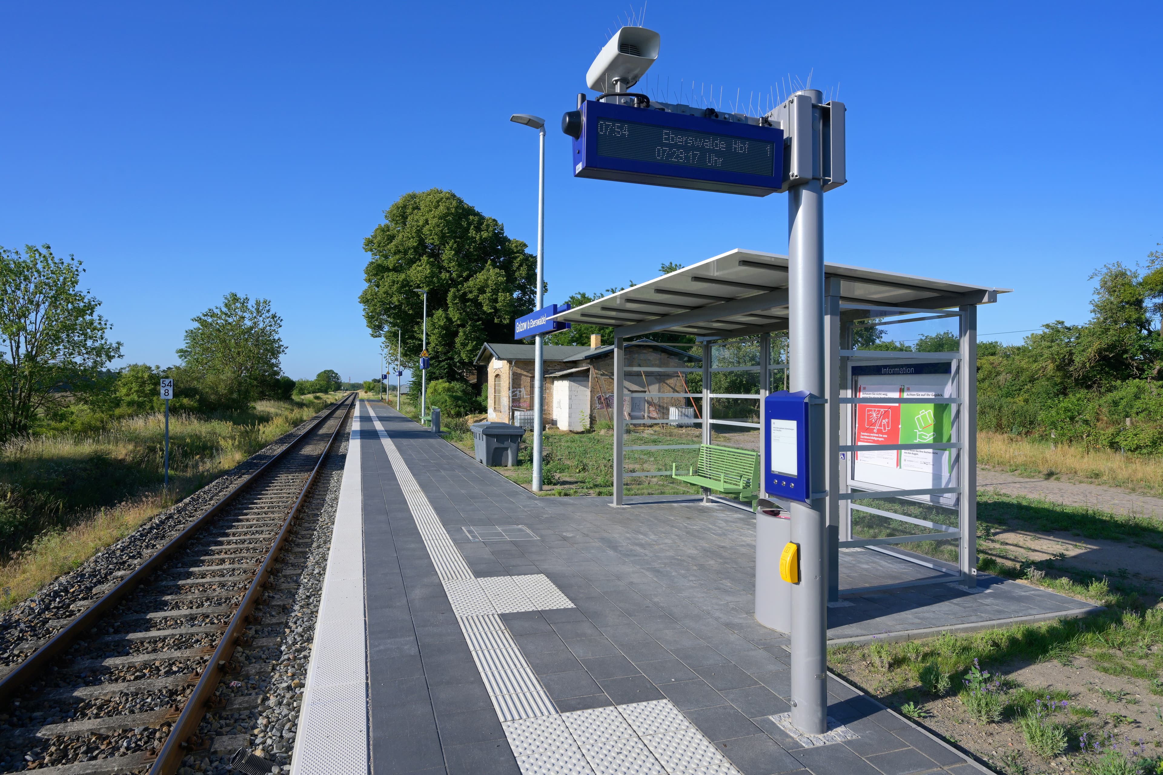 Ein Bahnsteig mit einer Sitzbank neben Gleisen.