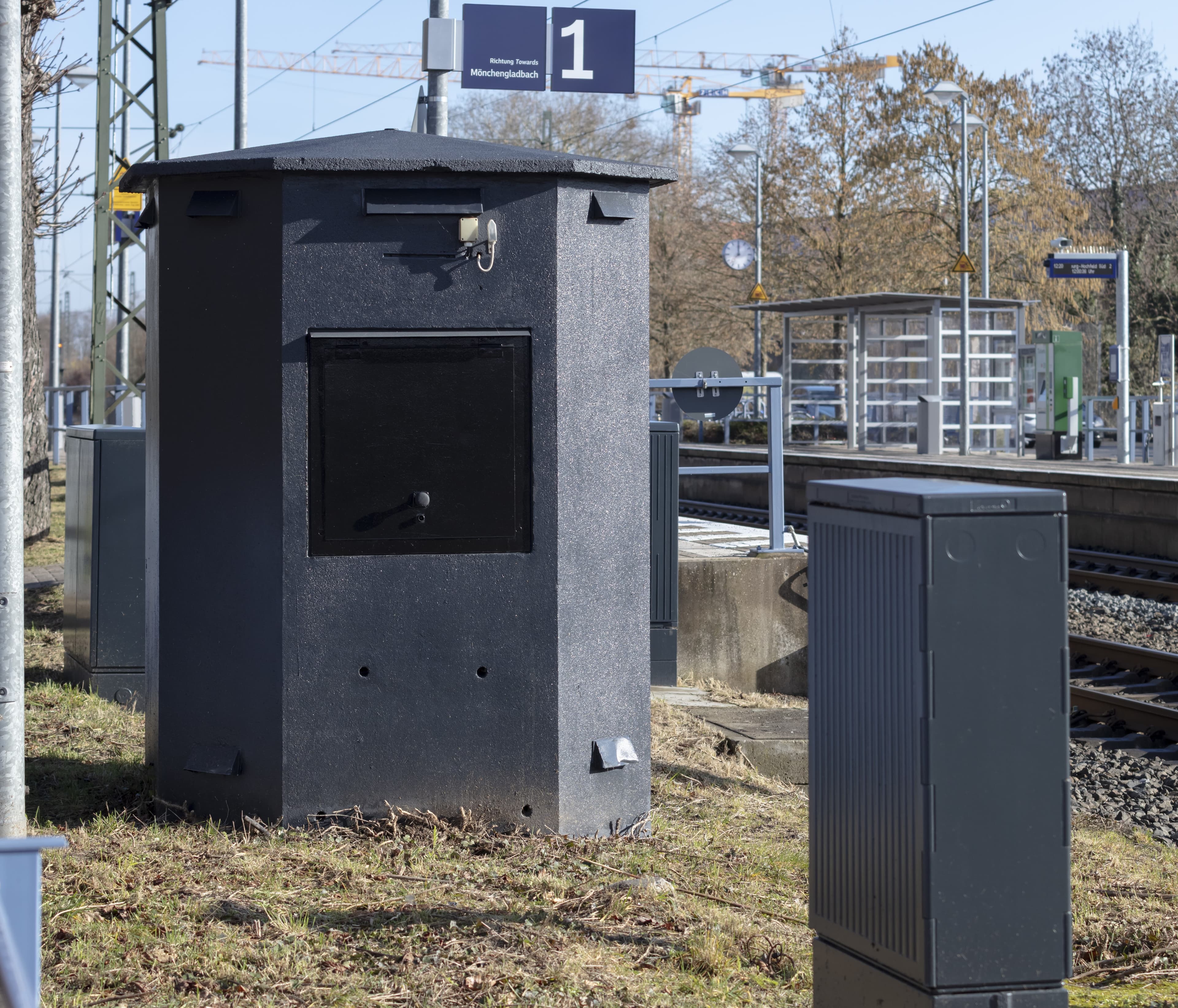 Schwarz gestrichenes Betonhäuschen und Stromkasten.