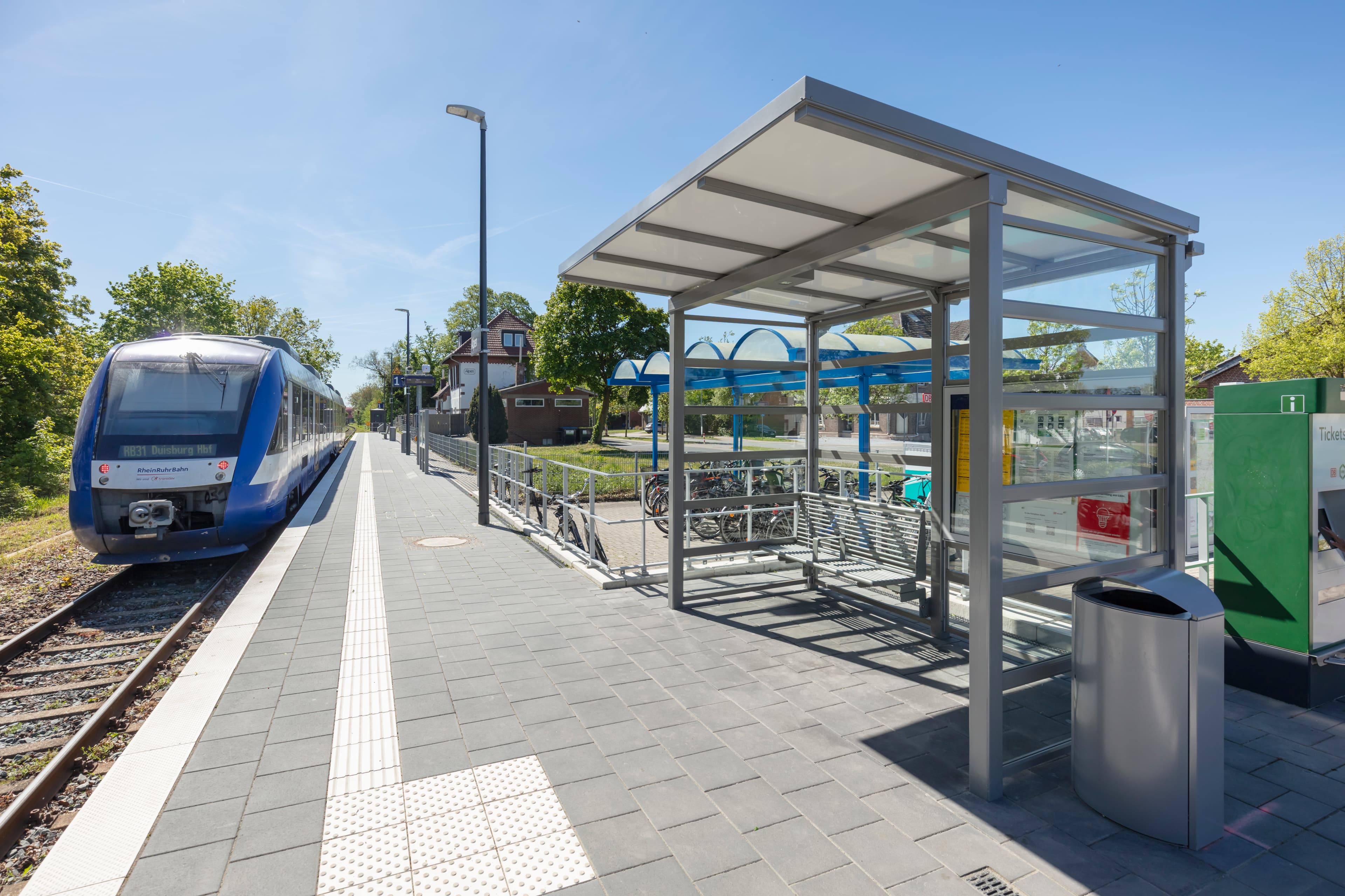Blick auf ein lichtdurchlässiges Wetterschutzhäuschen an einem Bahnsteig.