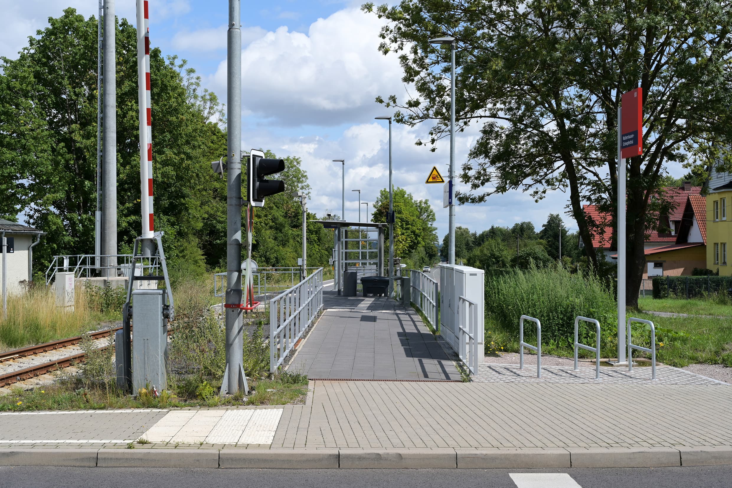 Die barrierefreie Zuwegung von der Straße zum Bahnsteig. rechts vom Eingang sind die Fahrradbügel, linkts die Schranken vom Bahnübergang.