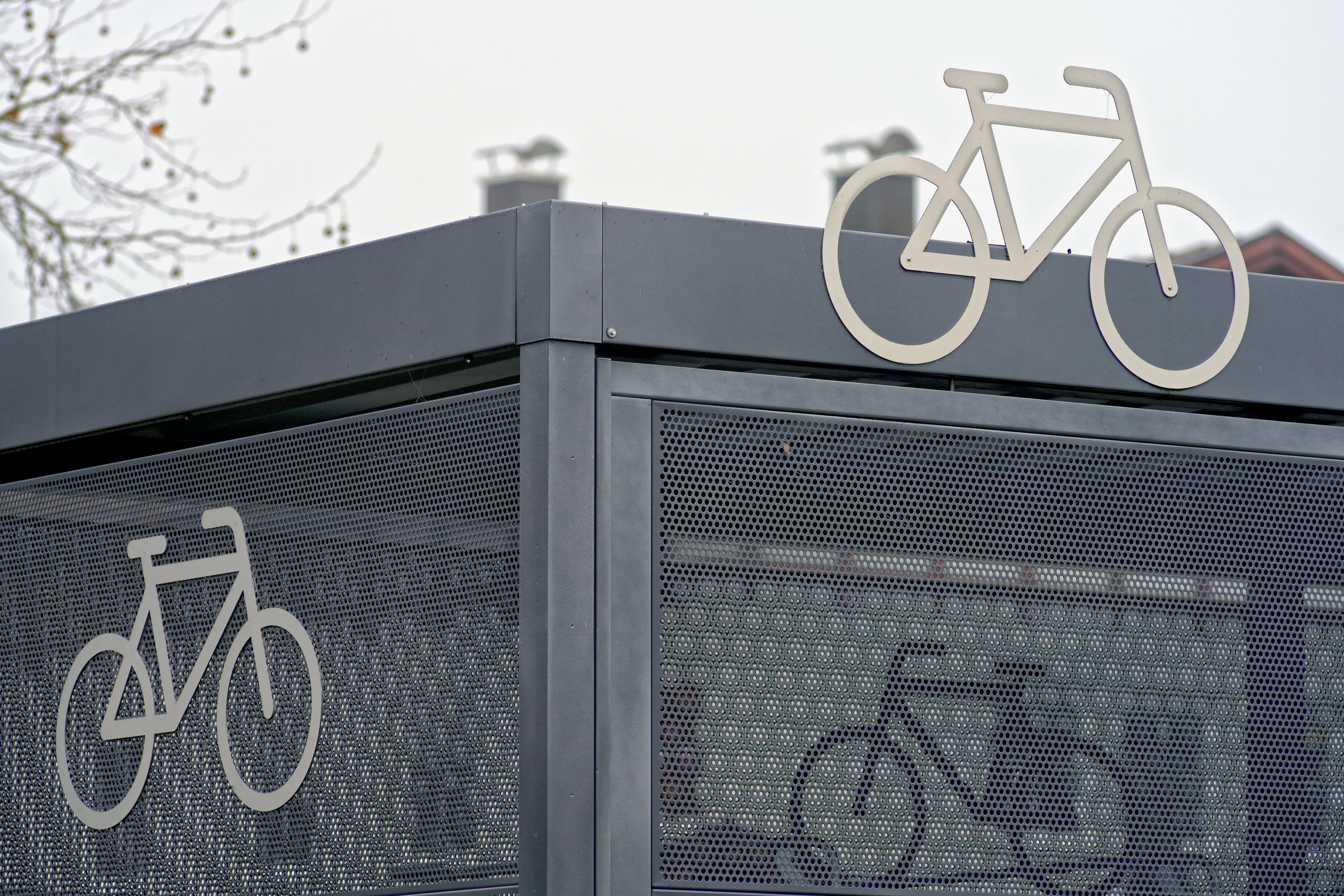 Abgebildet eine Fahrradeinhausung mit Wänden aus gelochtem Blech. Auf dieser sind mehrere Fahrradsymbole abgebildet.