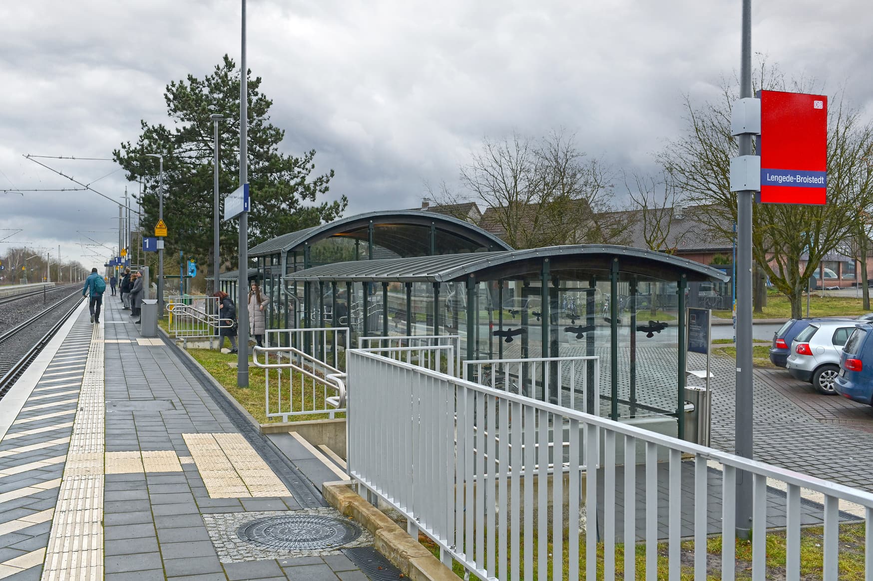 Bahnsteig mit taktilem Leitsystem, zwei Treppenaufgängen, vor einer Treppe ein verglaster Aufenthaltsraum.