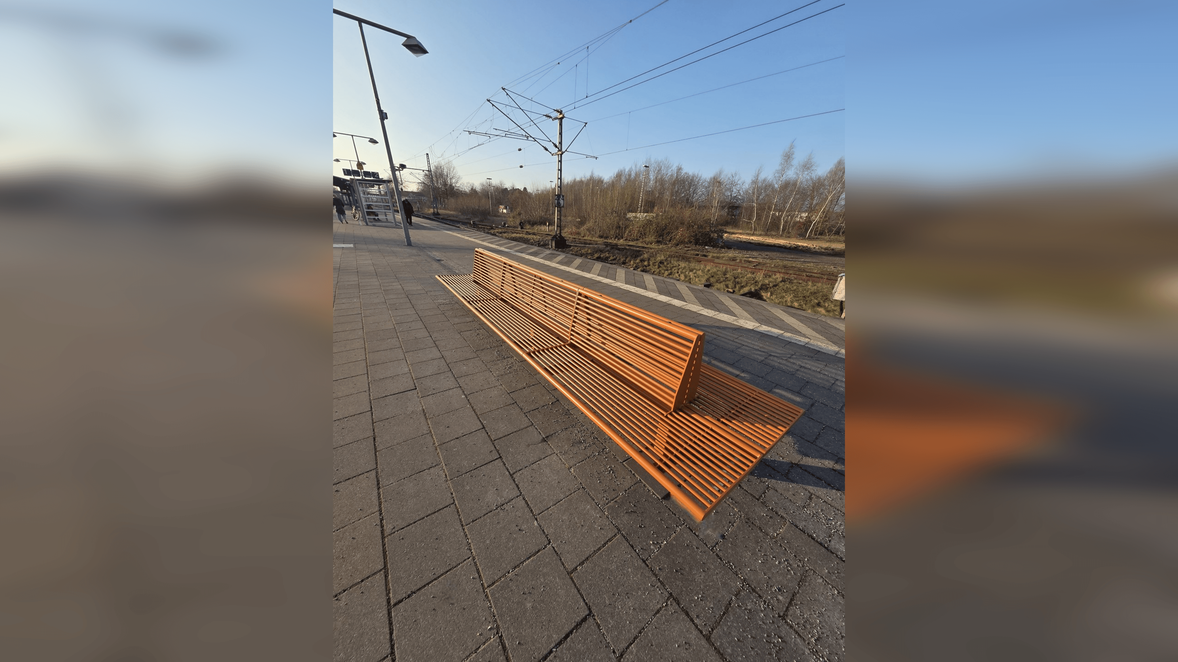 Eine orangene Bank auf dem Bahnsteig.