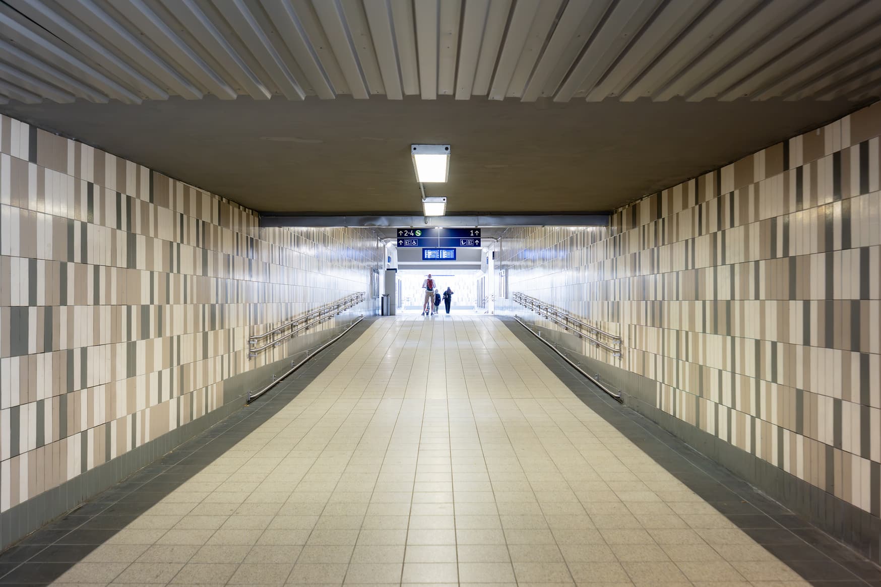Teil des Personentunnels, der in verschiedenen Grau- und Beigetönen gefliest ist. 