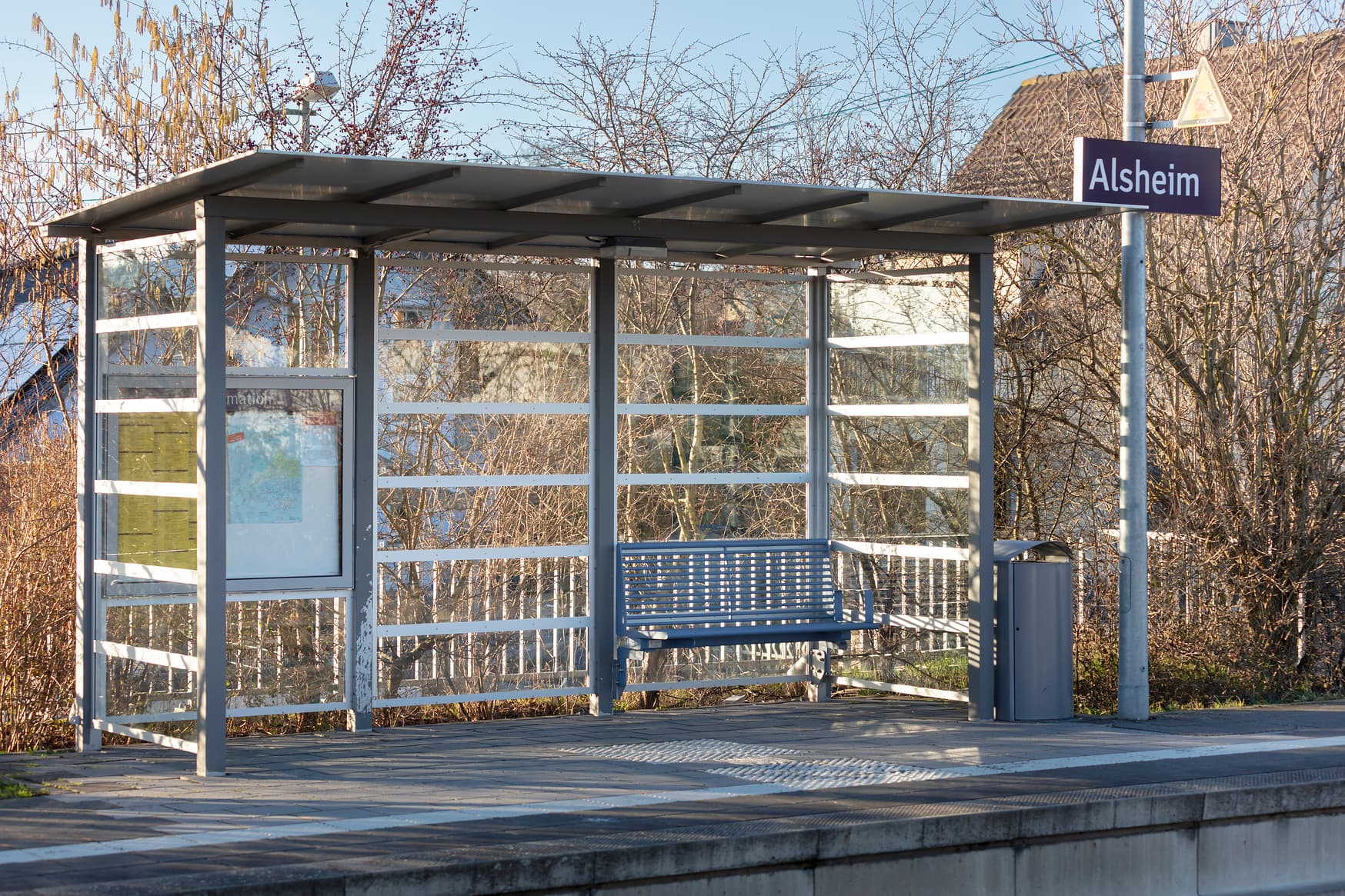 Blick auf ein Wetterschutzhäuschen am Bahnsteig. Darunter eine Sitzbank.