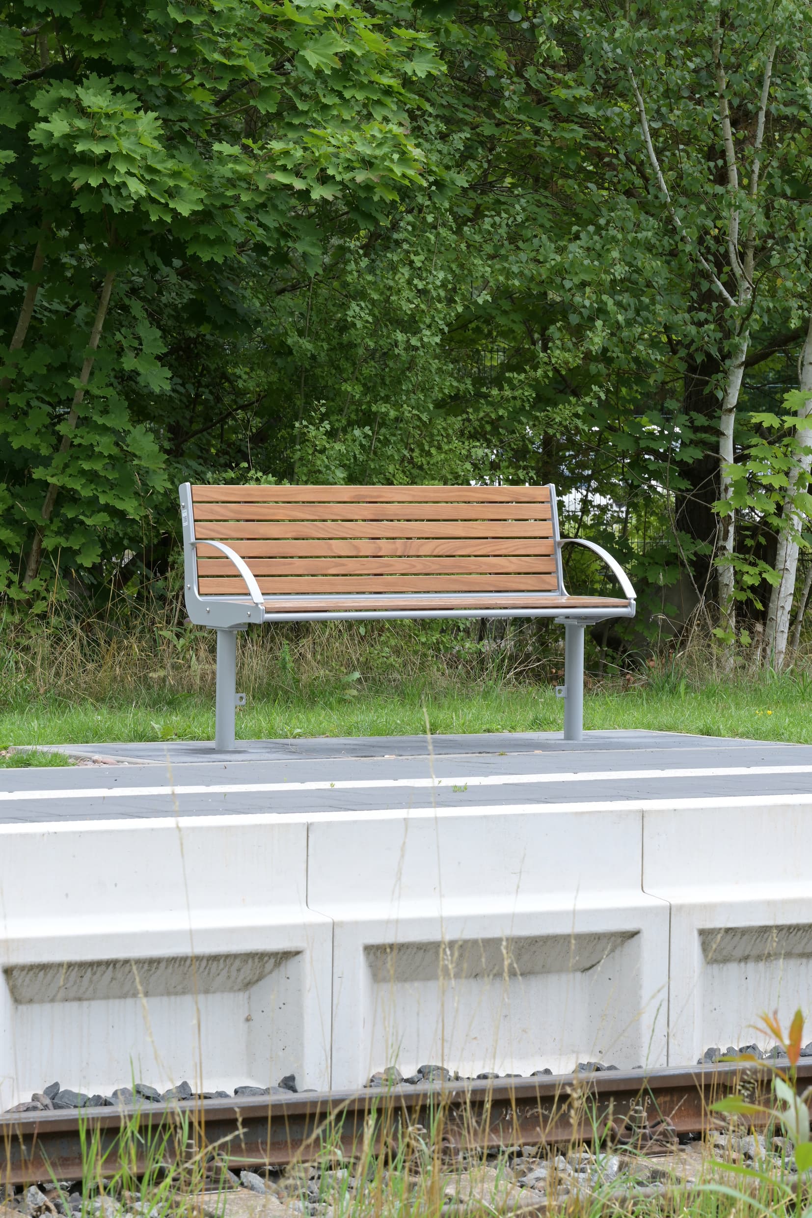 Einzeln stehende Holzbank auf dem Bahnsteig