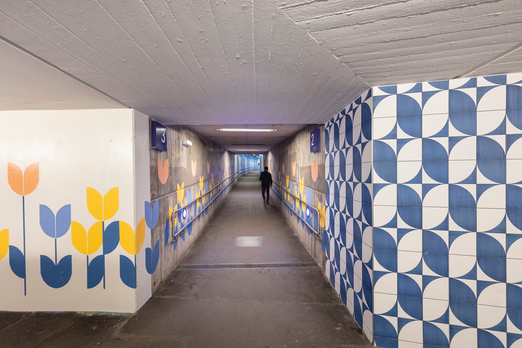 Personenunterführung mit blau-weißen Fliesen und gestalterischen Tulpenelementen.