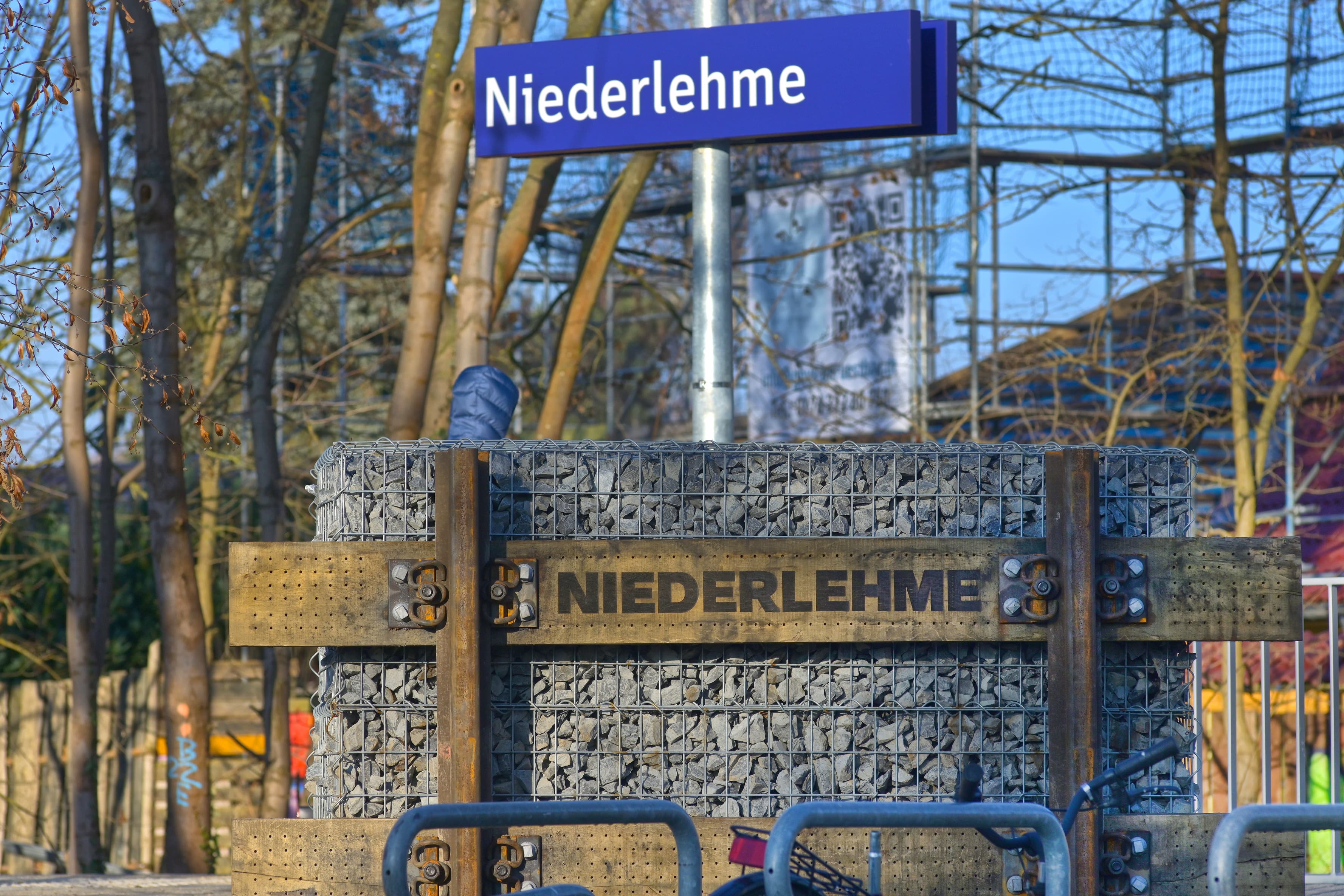 Zwei Bahnhofsschilder, eins in blau, eins aus Holz.
