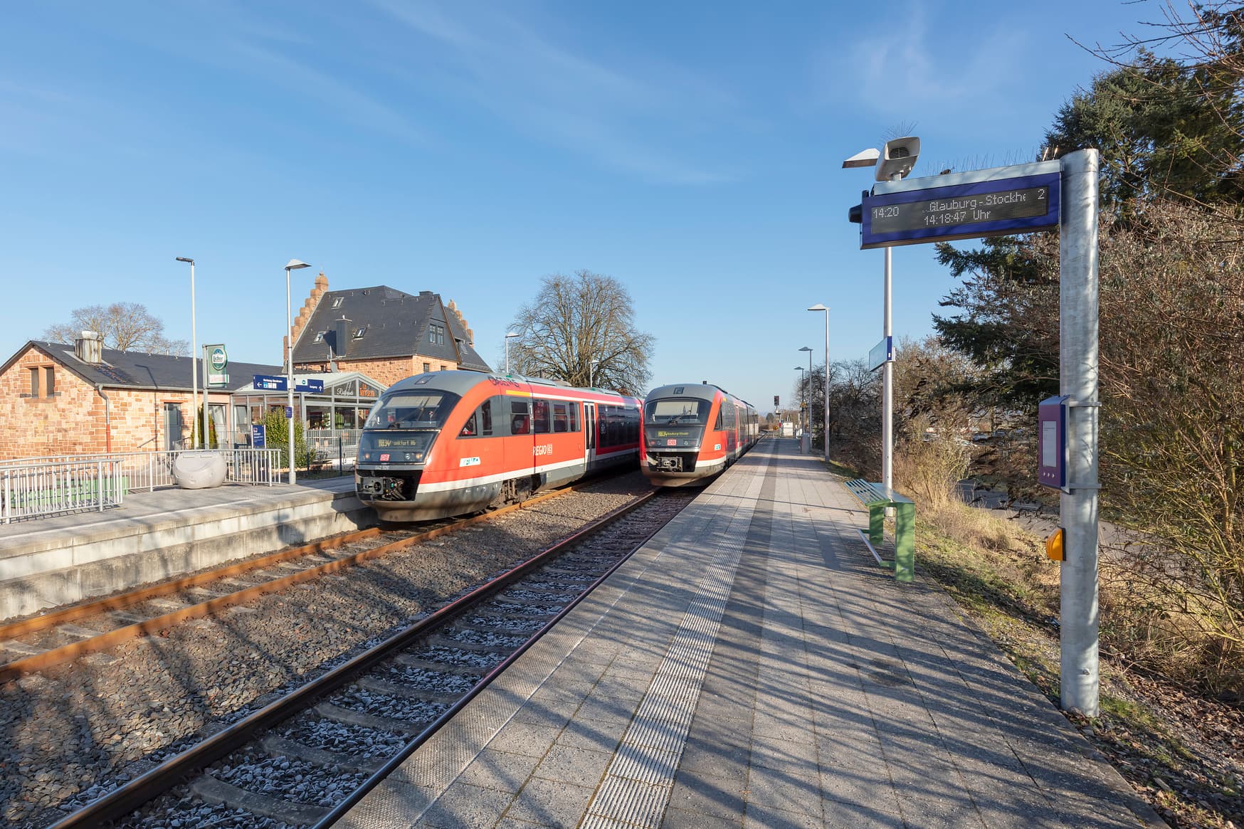Zwei Gleise und zwei Bahnsteige. Auf einem Bahnsteig ein dynamischer Schriftenanzeiger Plus mit Akustikmodul.