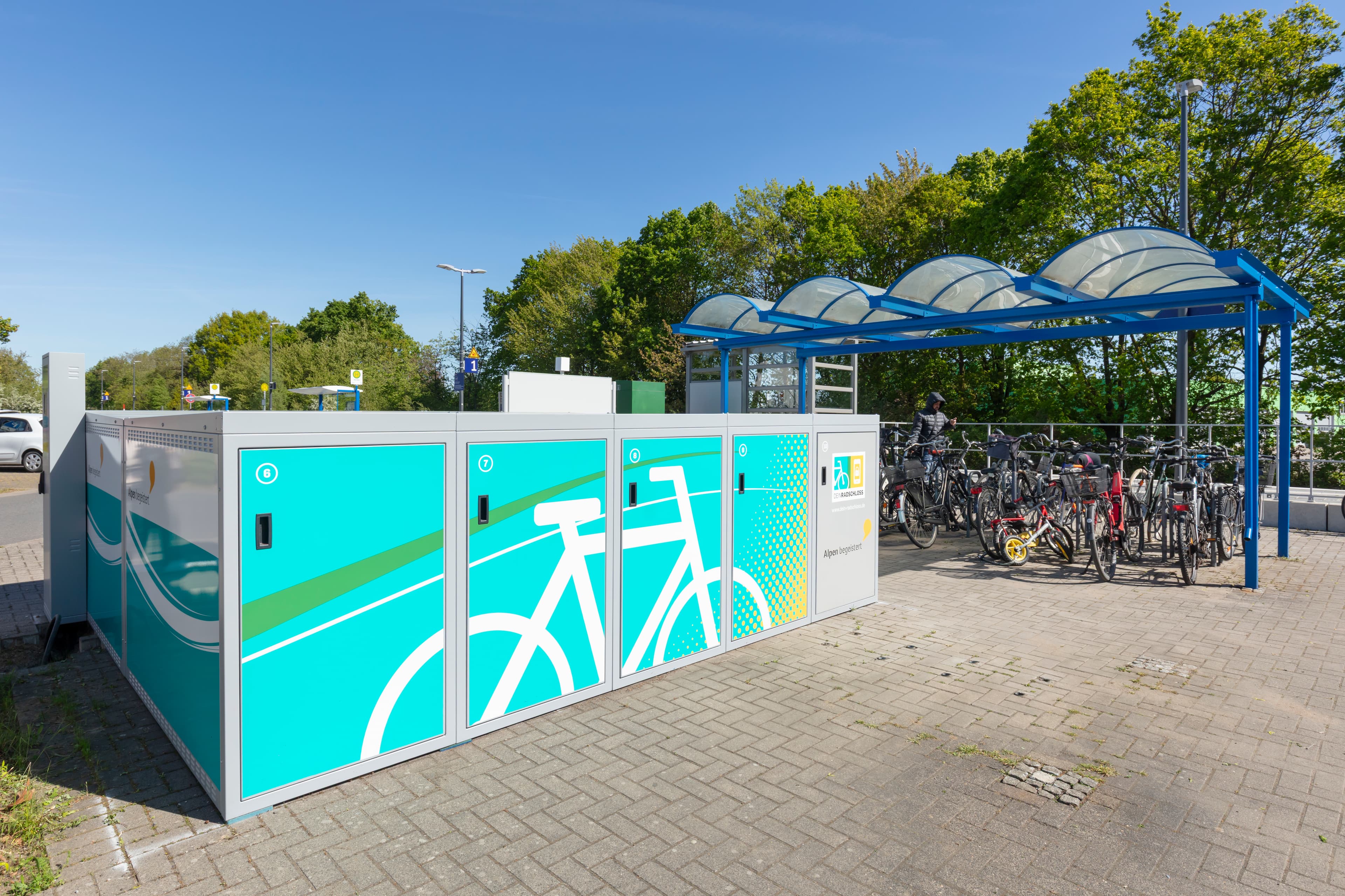 Blick auf eine Fahrradbox. Dahinter ein überdachter Fahrradabstellplatz.