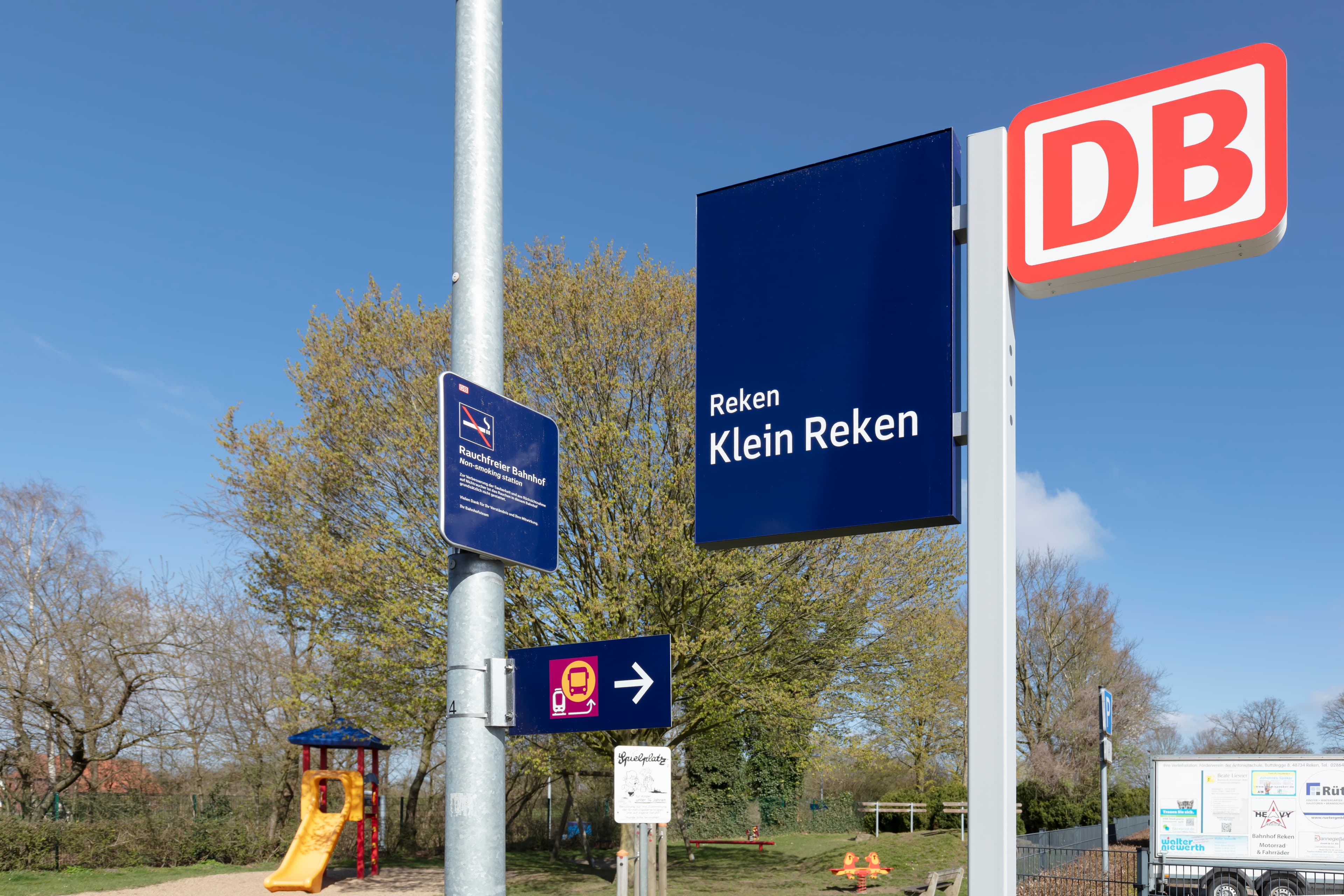 Blaue Beschilderung mit weißer Schrift. Im Hintergrund ein Spielplatz.