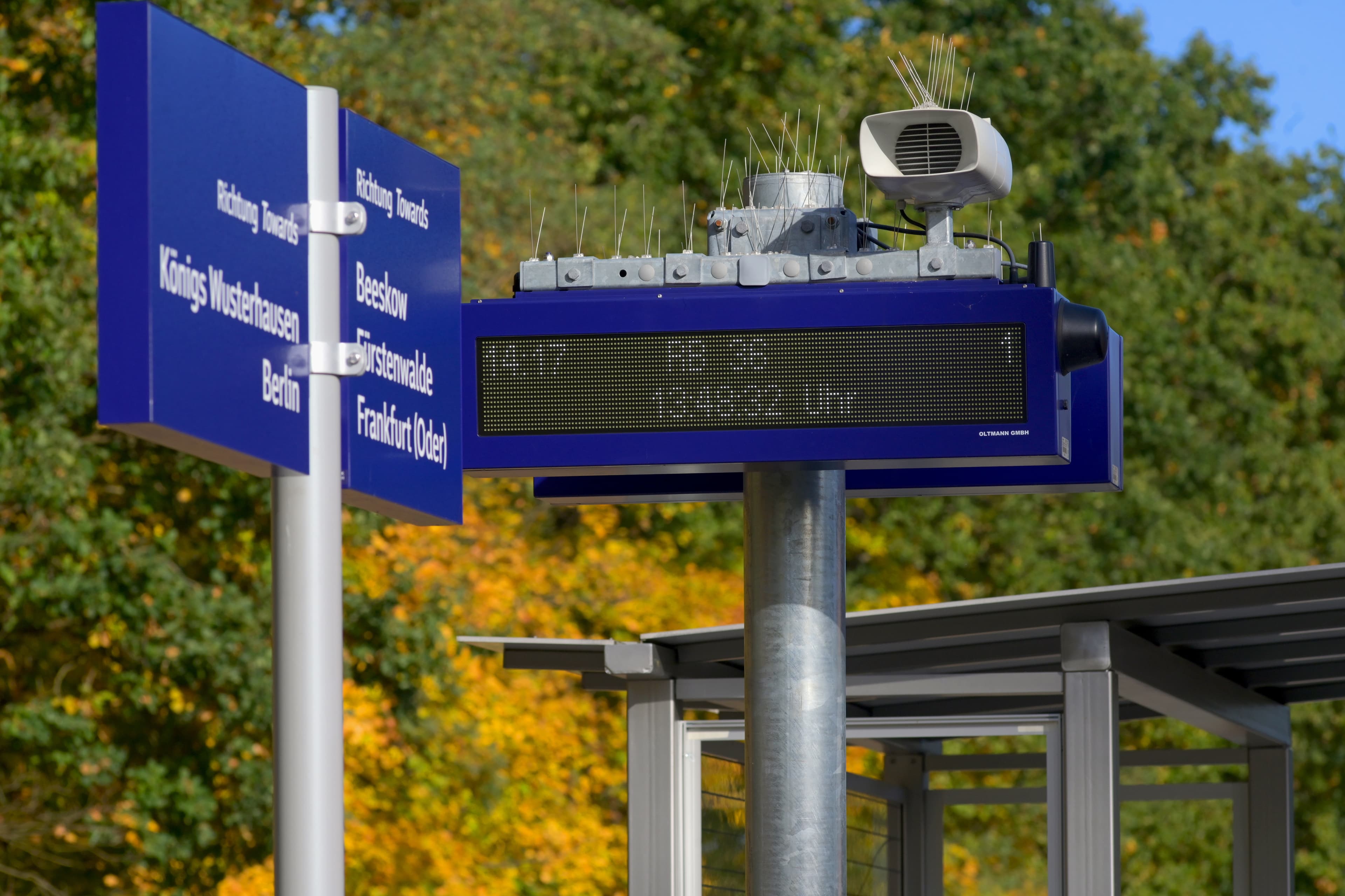 Blick auf blaue Beschilderung und einen Bildschirm mit Reiseinformationen.