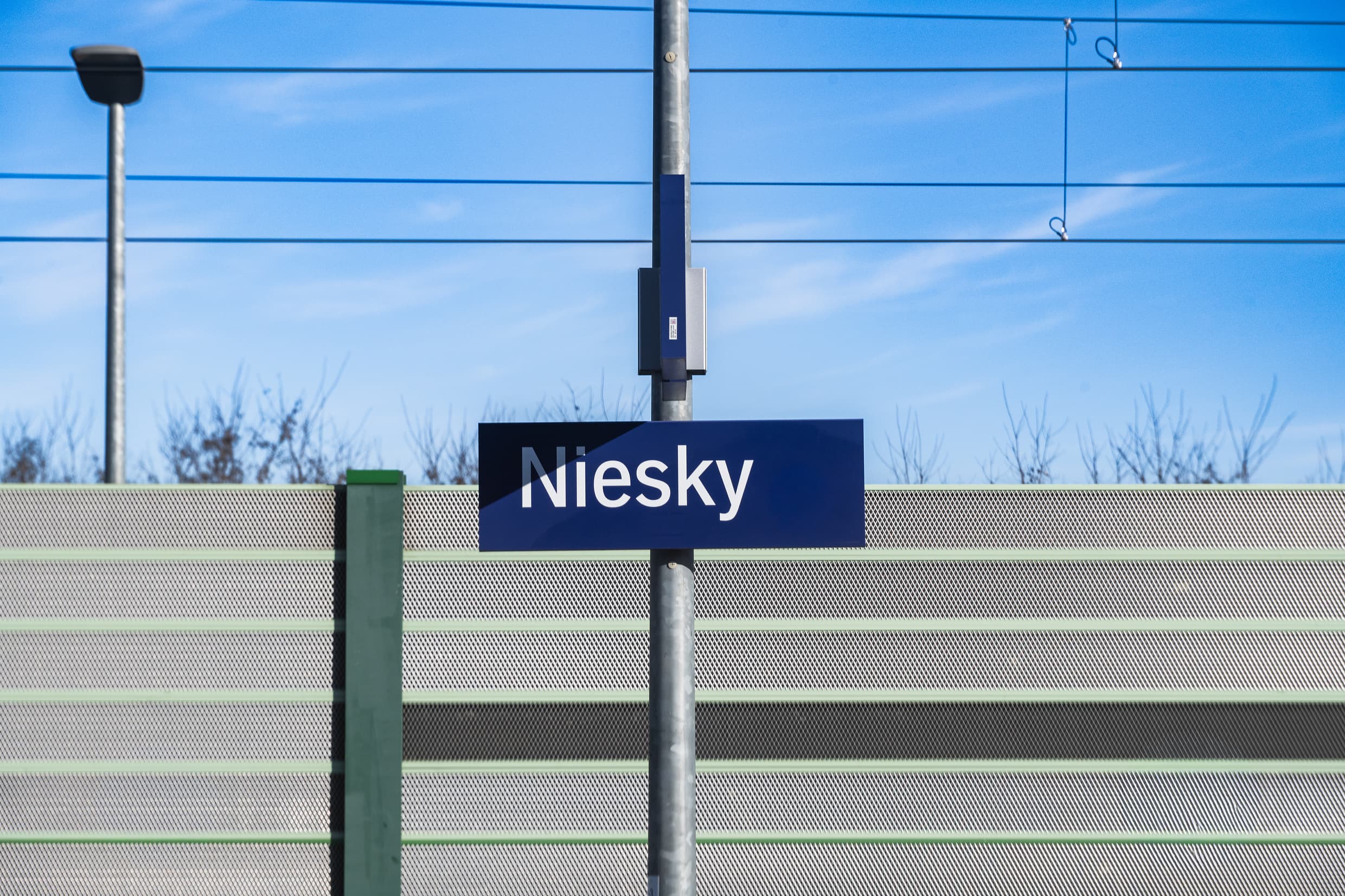 Bahnhofsnamensschild mit dem Bahnhofsnamen Niesky. Weiße Schrift auf blauem Untergrund