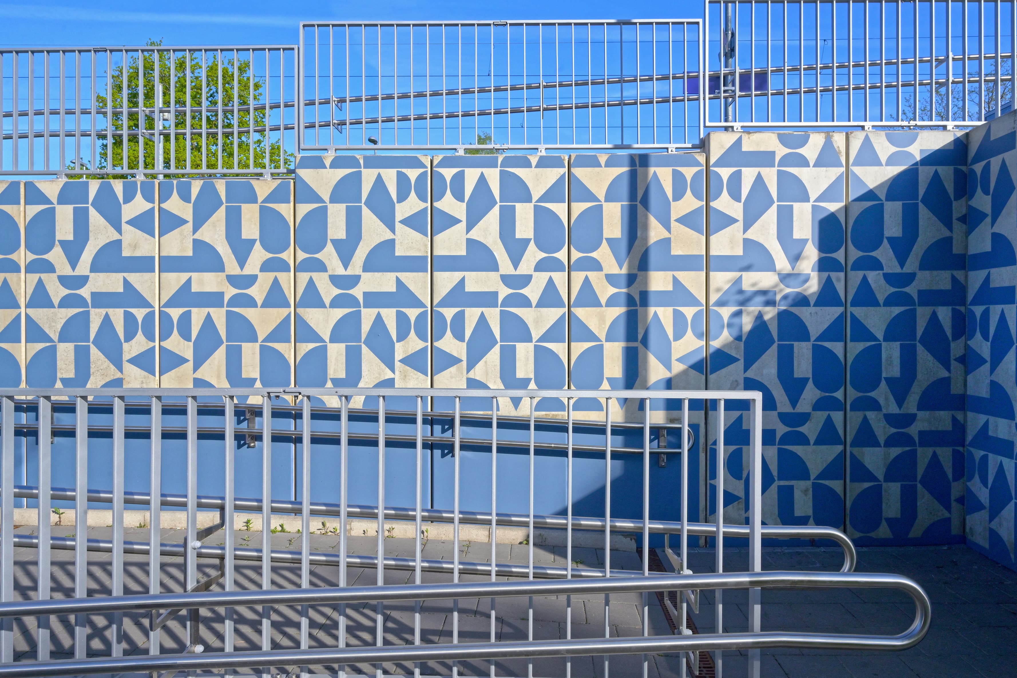 Im Bild ist eine Rampe zum Bahnsteig dargestellt, die farblich-geometrisch gestaltet wurde.