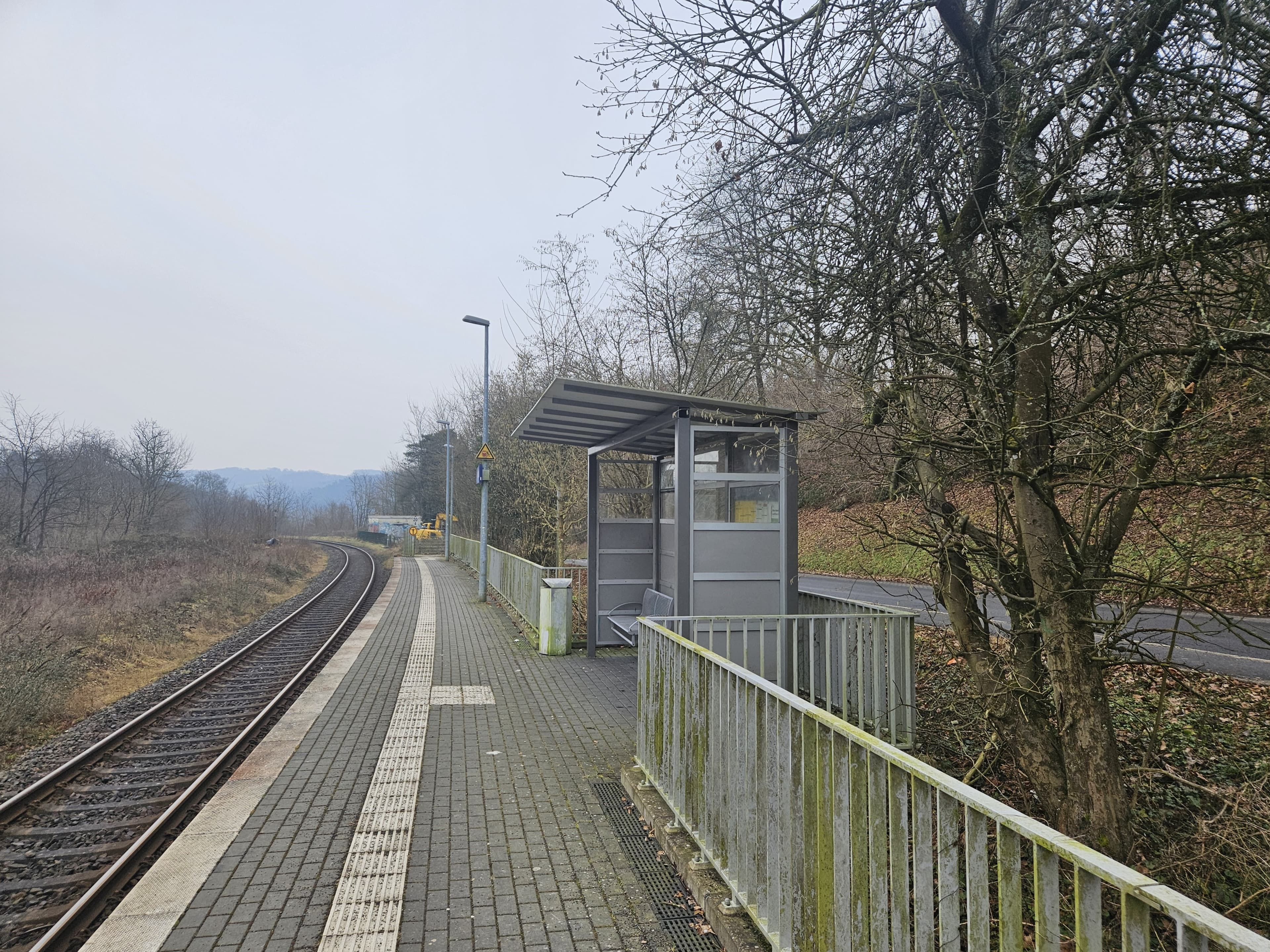 Blick auf das alte Wetterschutzhäuschen vor der Modernisierung. Mittig befindet sich der Beinsteig und links davon das Gleis.