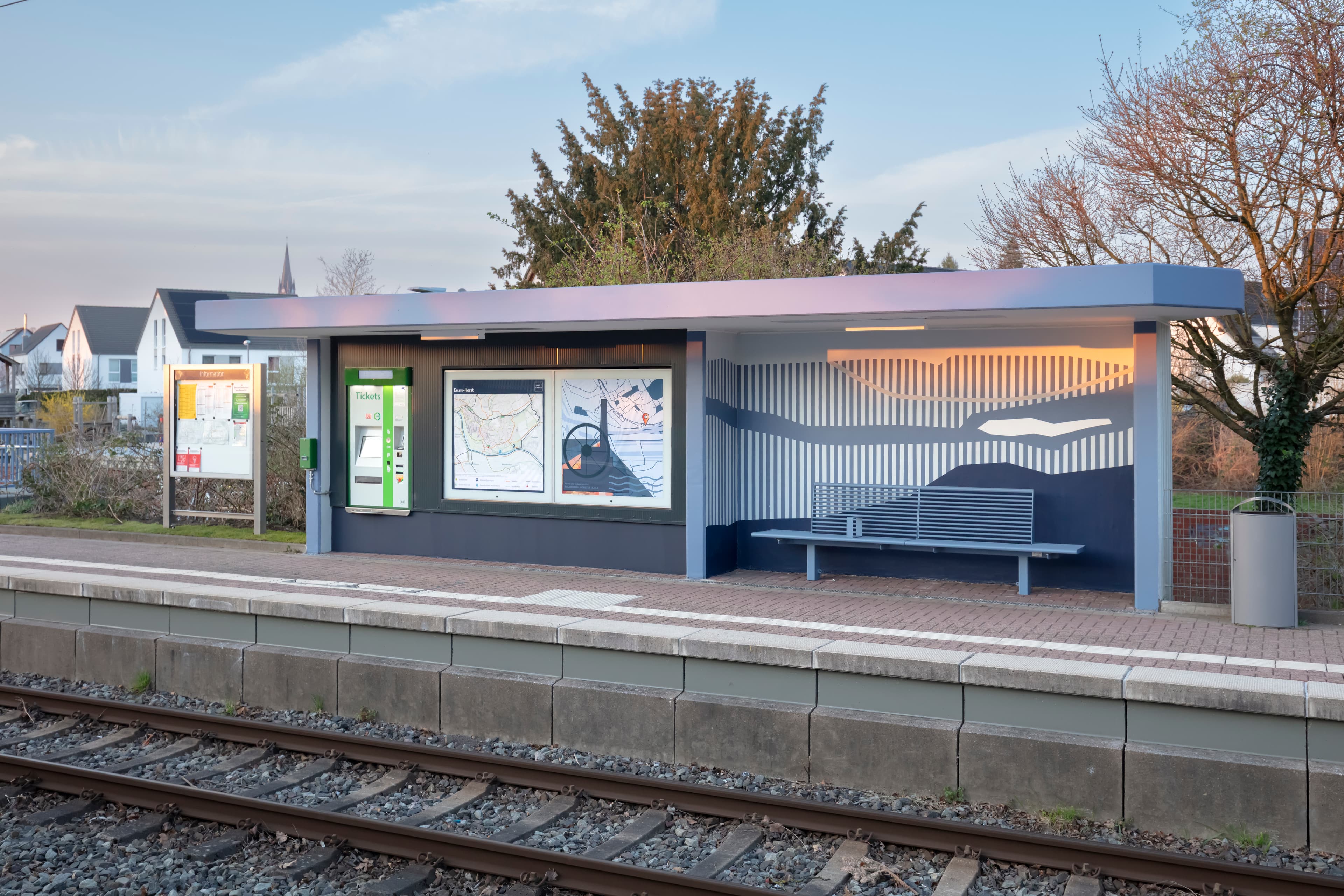 Blaues Wetterschutzhäuschen auf einem Bahnsteig.