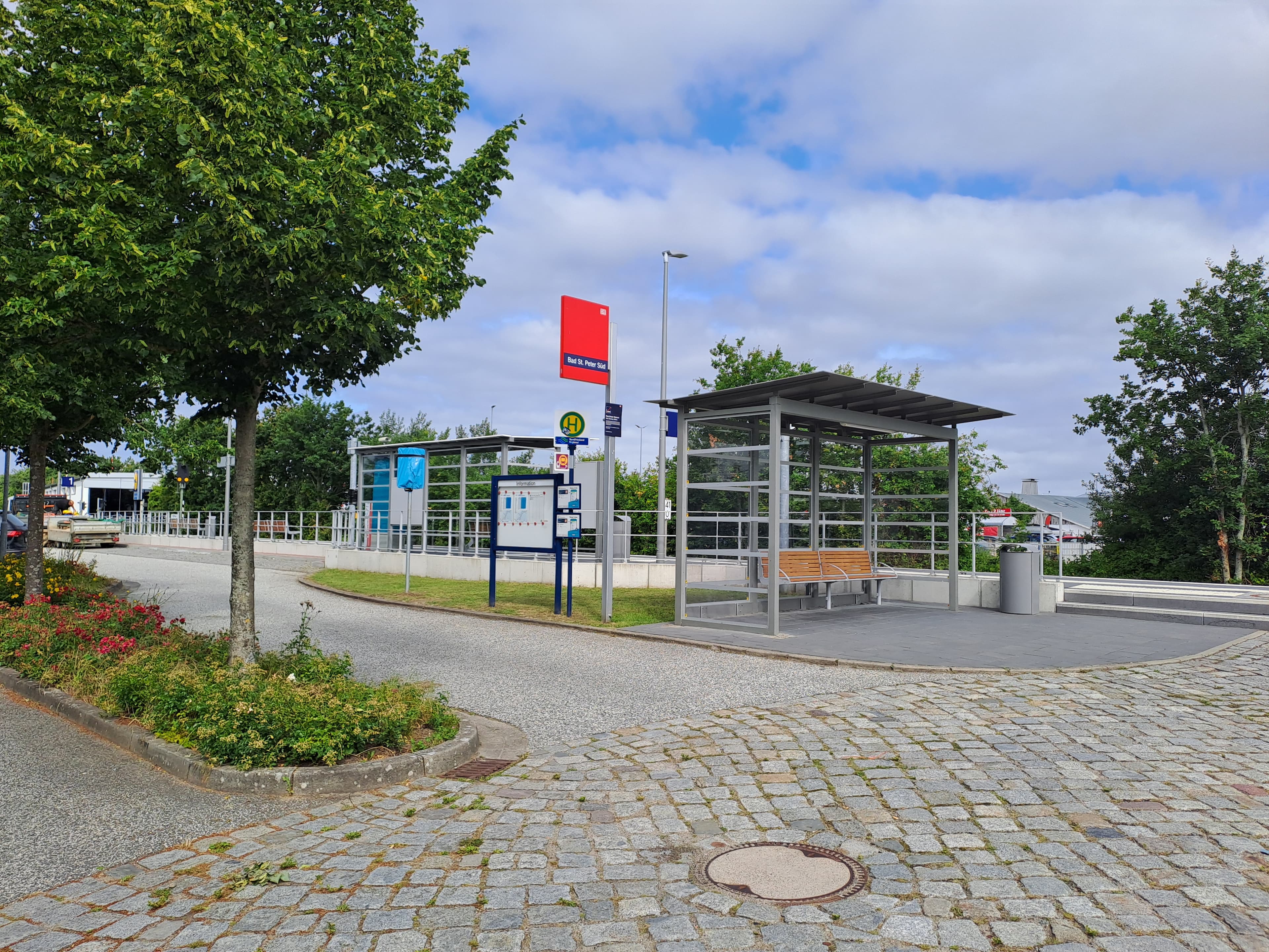 Der gepflasterte Vorplatz des Bahnhofs nebst Blumenrabatten.