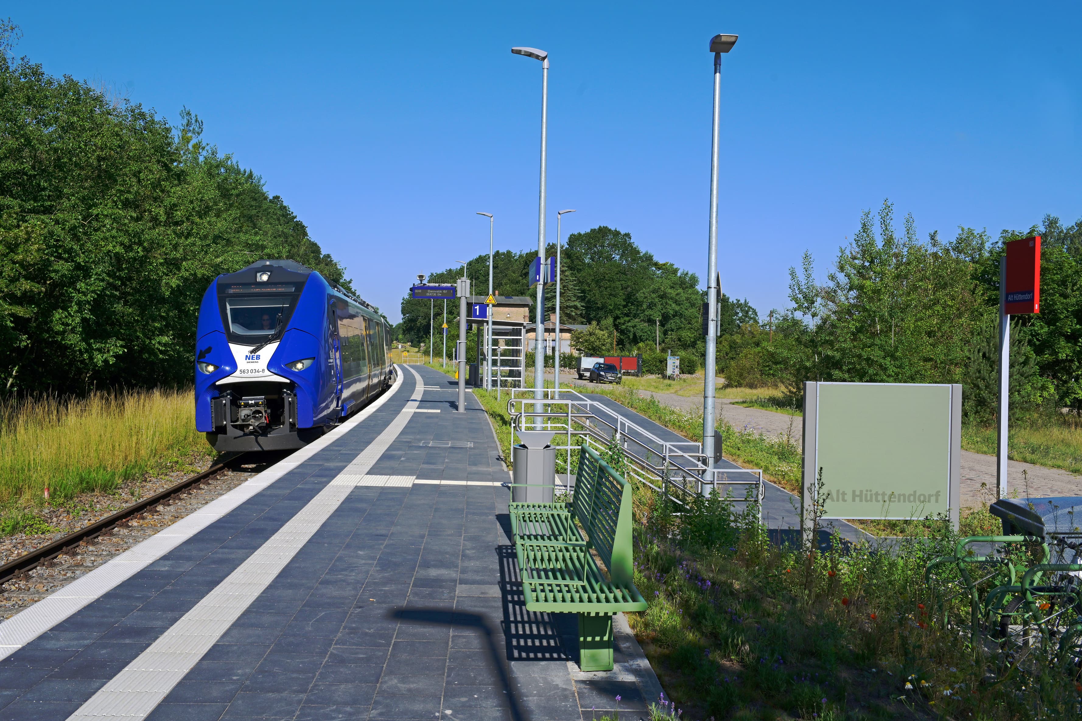 Der Blick auf einen einfahrenden Zug am Bahnsteig der Station Alt Hüttendorf.