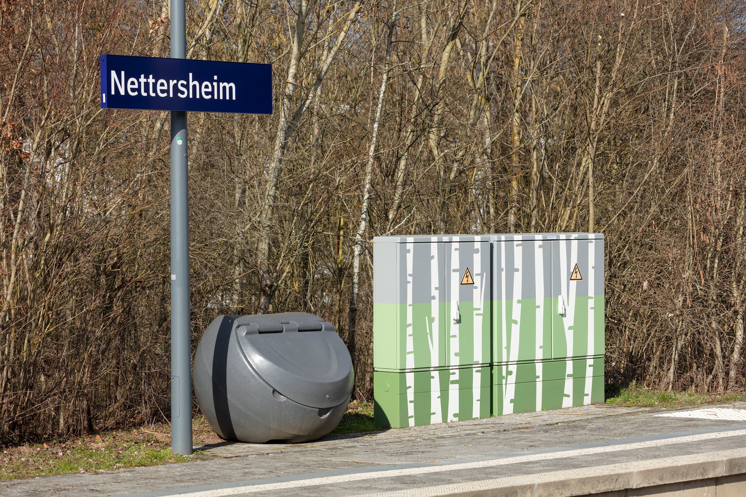 Stromkästen mit Birkenmotiven an einem Bahnsteig.