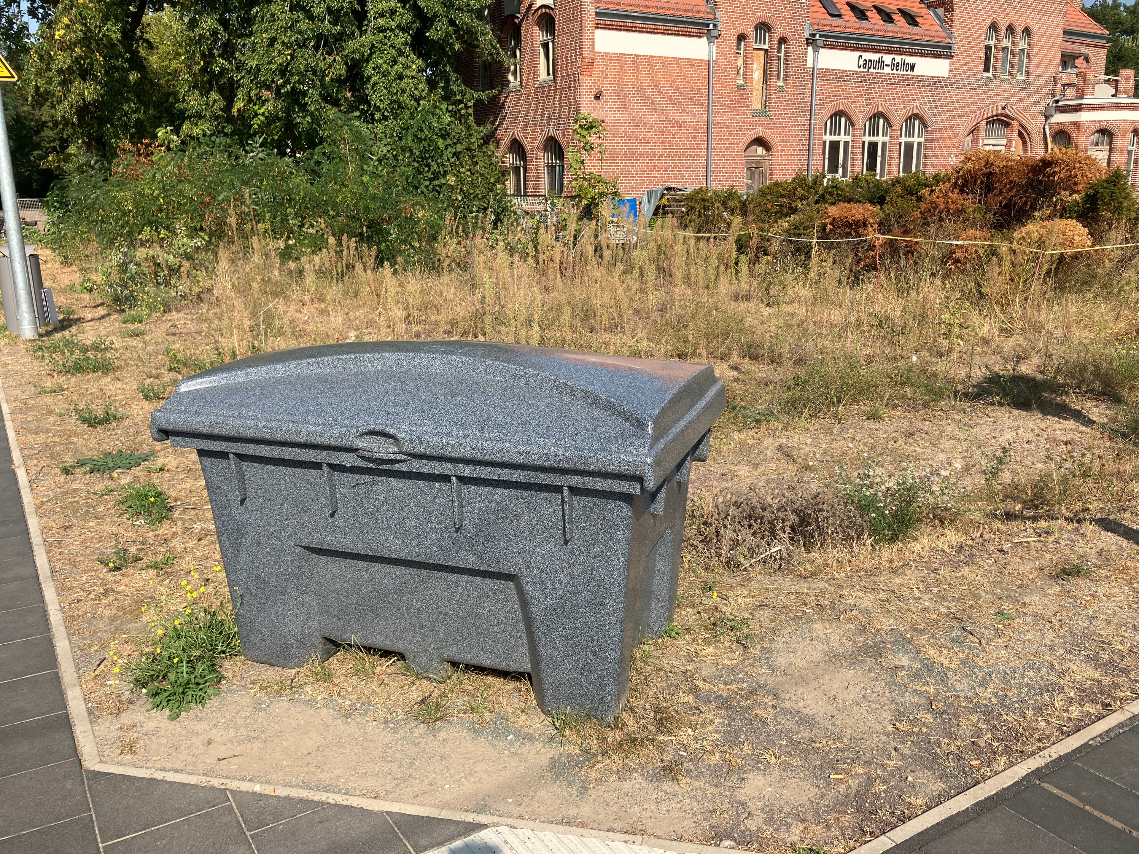 Ein Streugutbehälter auf einer trockenen Wiese.