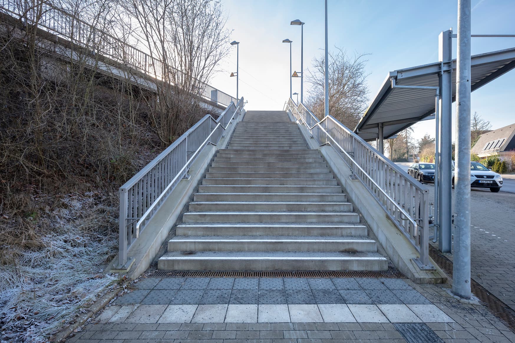 Treppe zum Bahnsteig mit hohen Lampen.