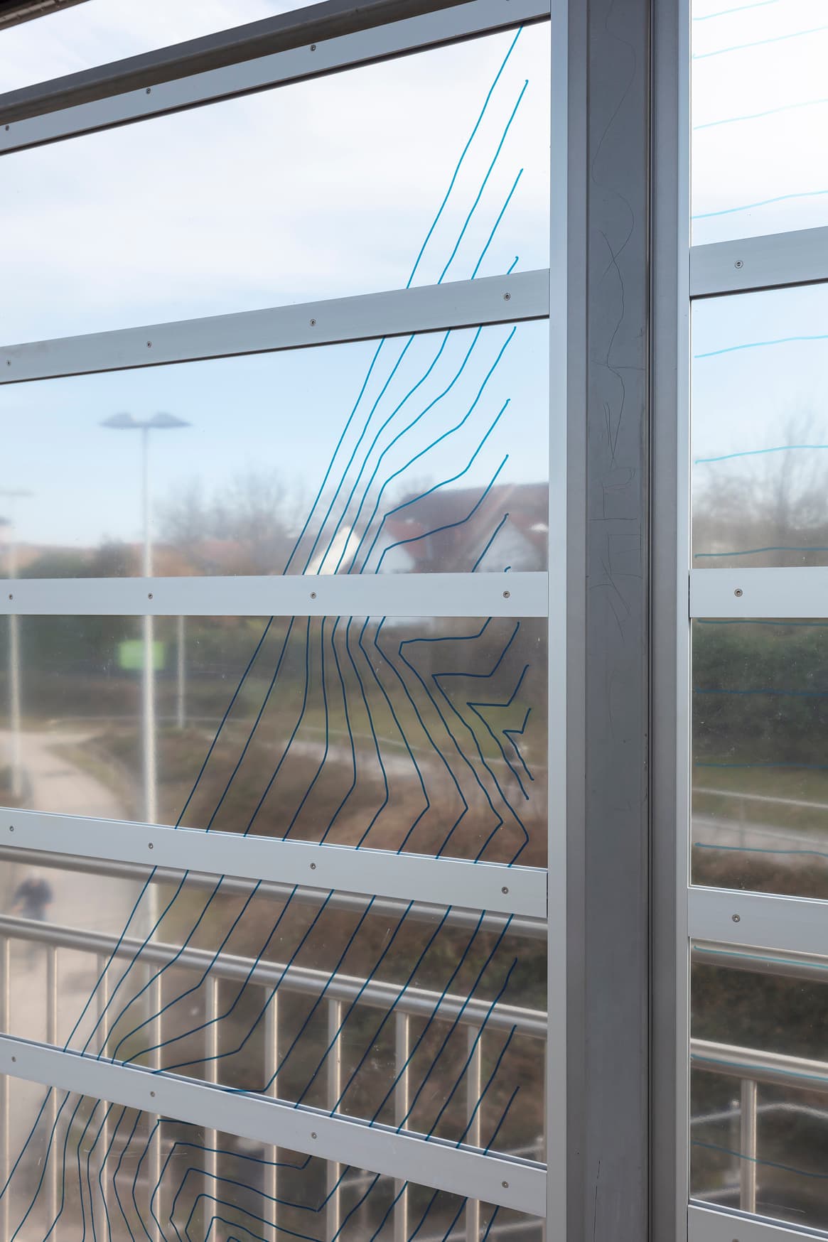 Detailaufnahme einer Glaspanele vom Windschutz. Darauf ein dezentes Rastermuster in blauer Farbe.