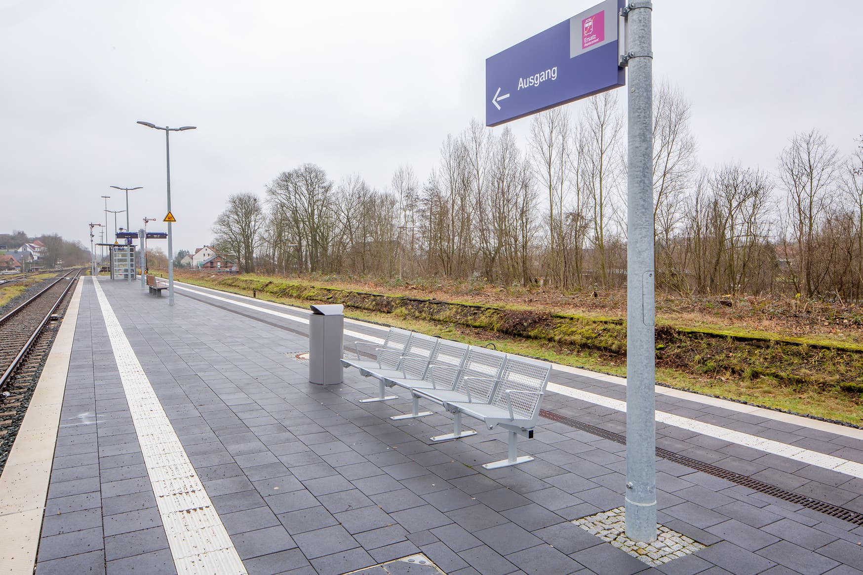 Blick auf den Bahnsteig Scherfede mit Bahnhofsschild für Ausgang und Schienenersatzverkehr.