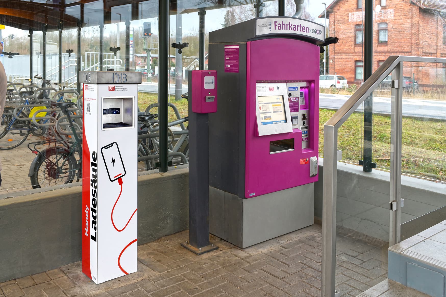 Handyladesäule neben lilafarbenem Ticketautomat im Zugangsbereich.