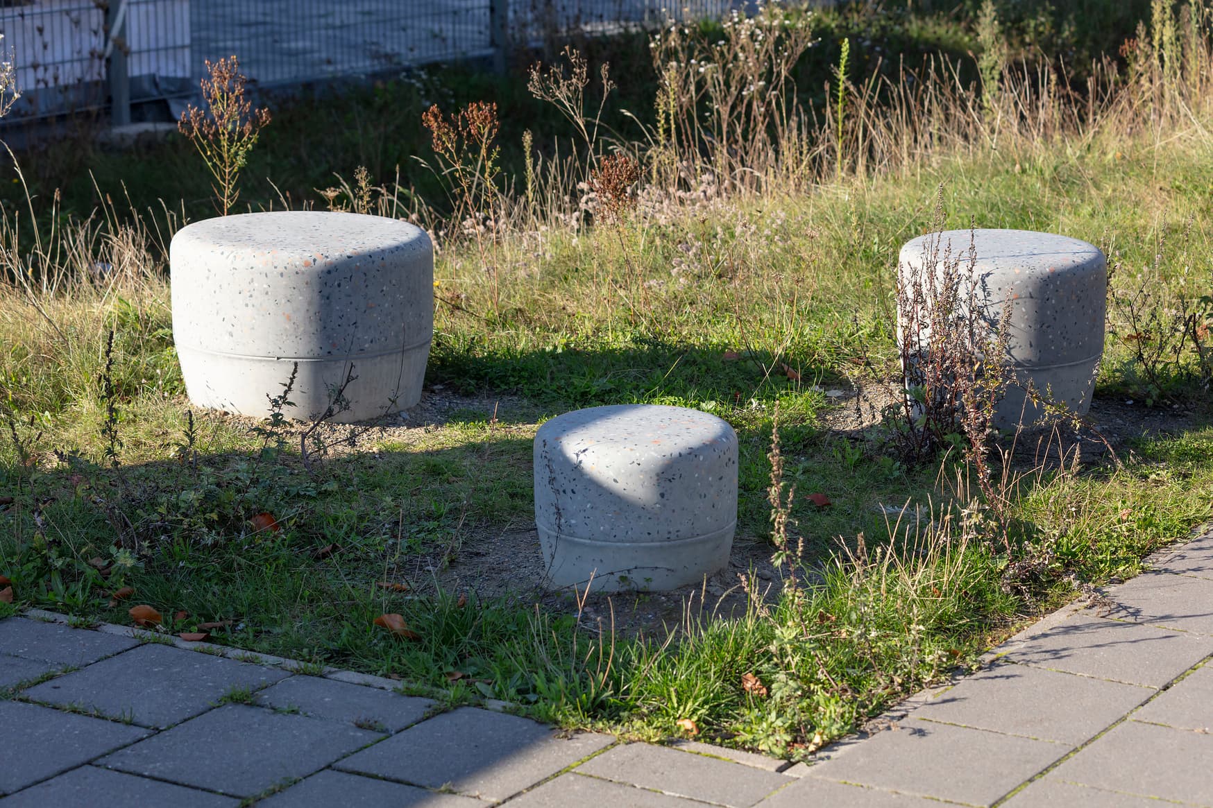 Drei Betonhocker auf einer Wiese.