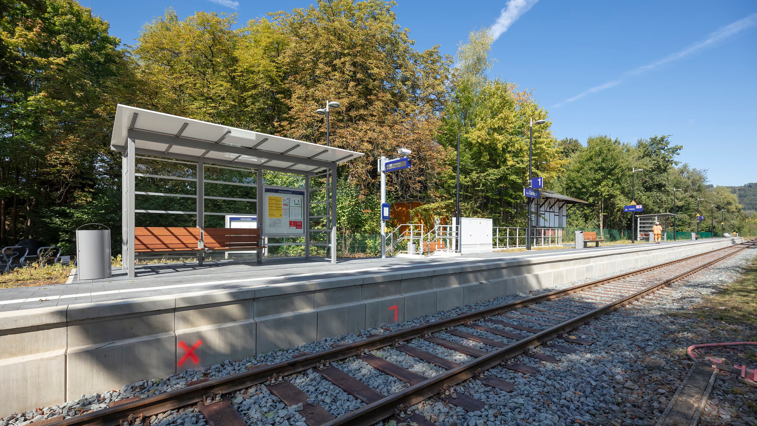 Blick auf den modernisierten Bahnsteig mit neuem Wetterschutzhäuschen, neuen Sitzgelegenheiten und einem neuen Dynamischen Schriften Anzeiger (DSA+)