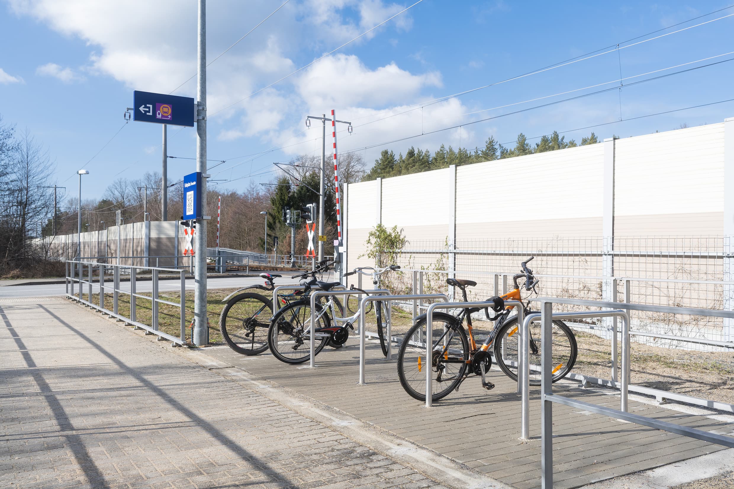Blick auf Fahrradbügel. Im Hintergrund ist ein Bahnübergang zu sehen.
