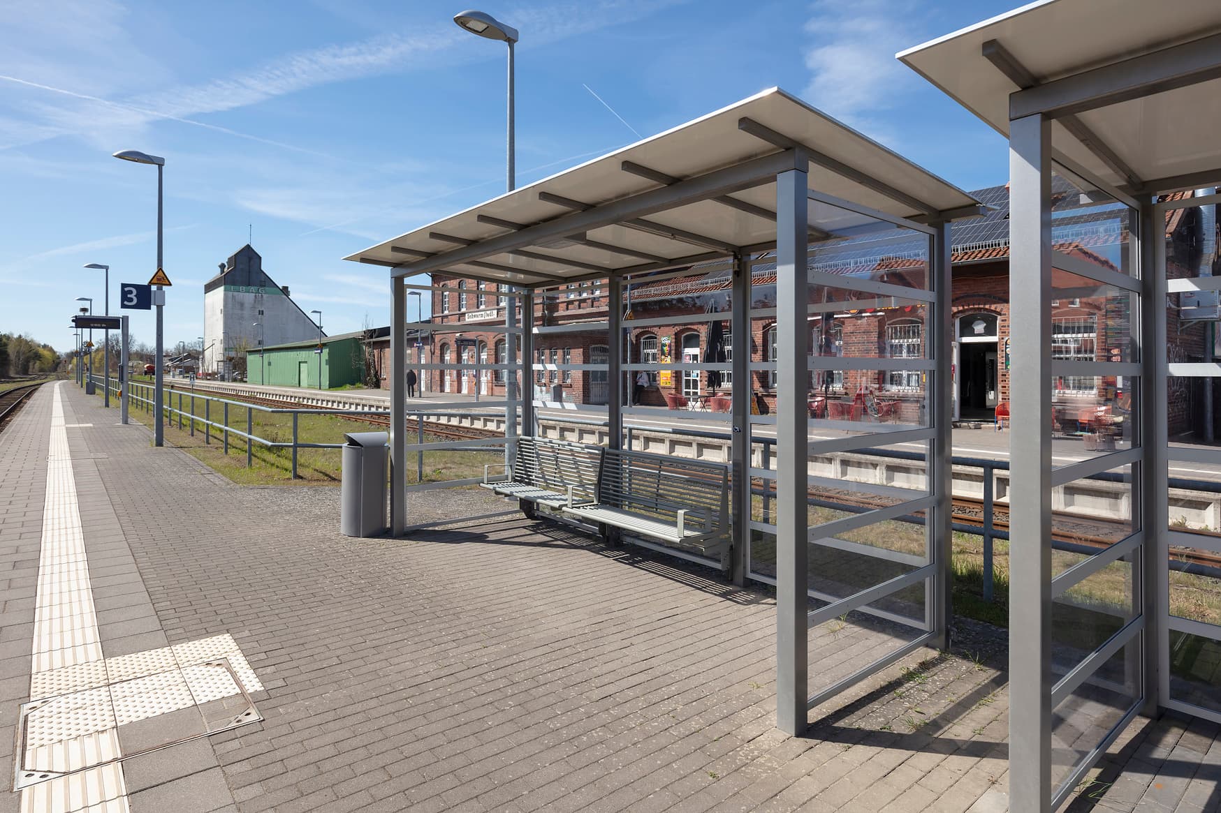 Wetterschutzhäuschen mit Sitzbank auf einem Bahnsteig.