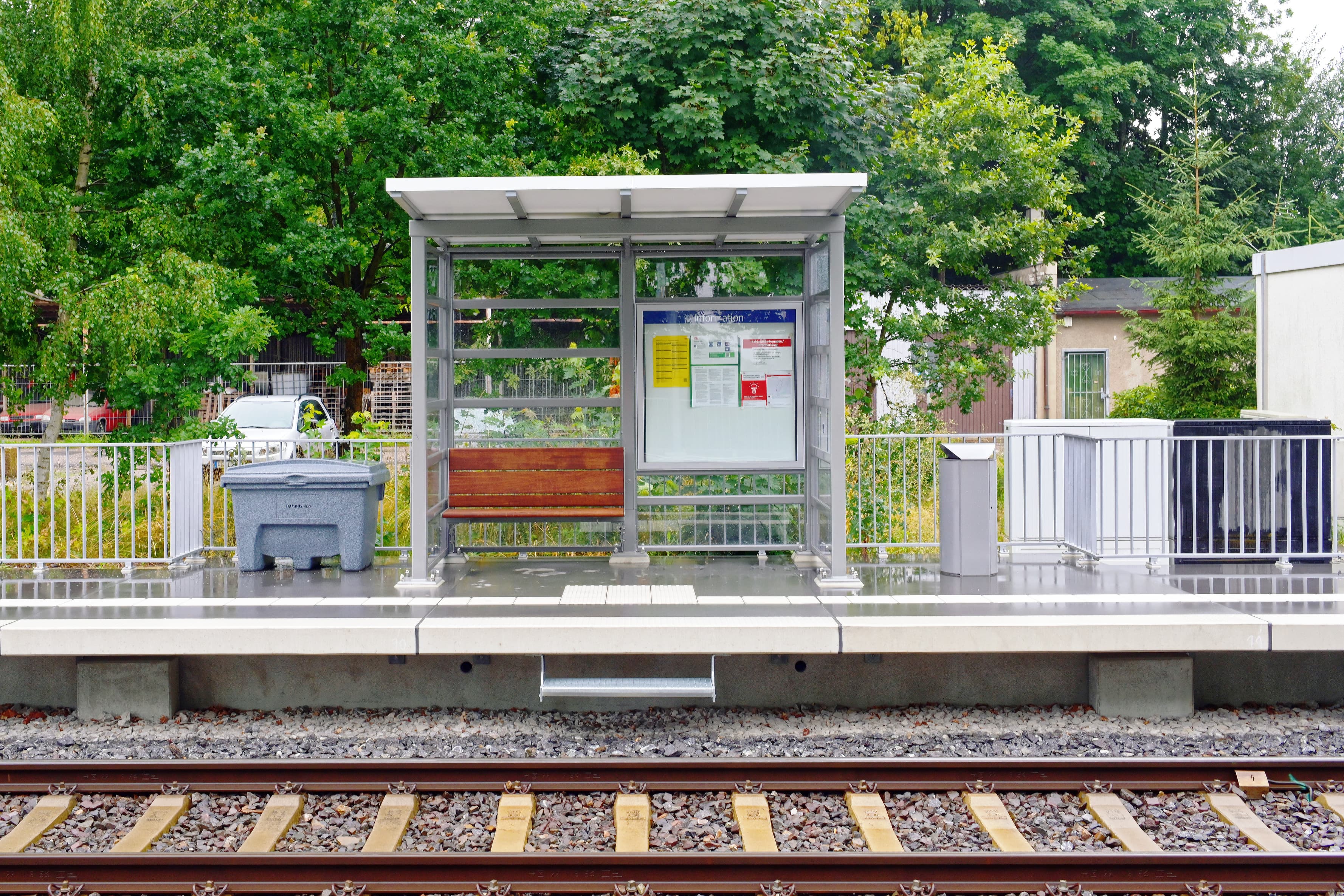 Zu sehen ist ein Wetterschutzhaus mit transparenten Wänden und einer neuen Sitzbank. 