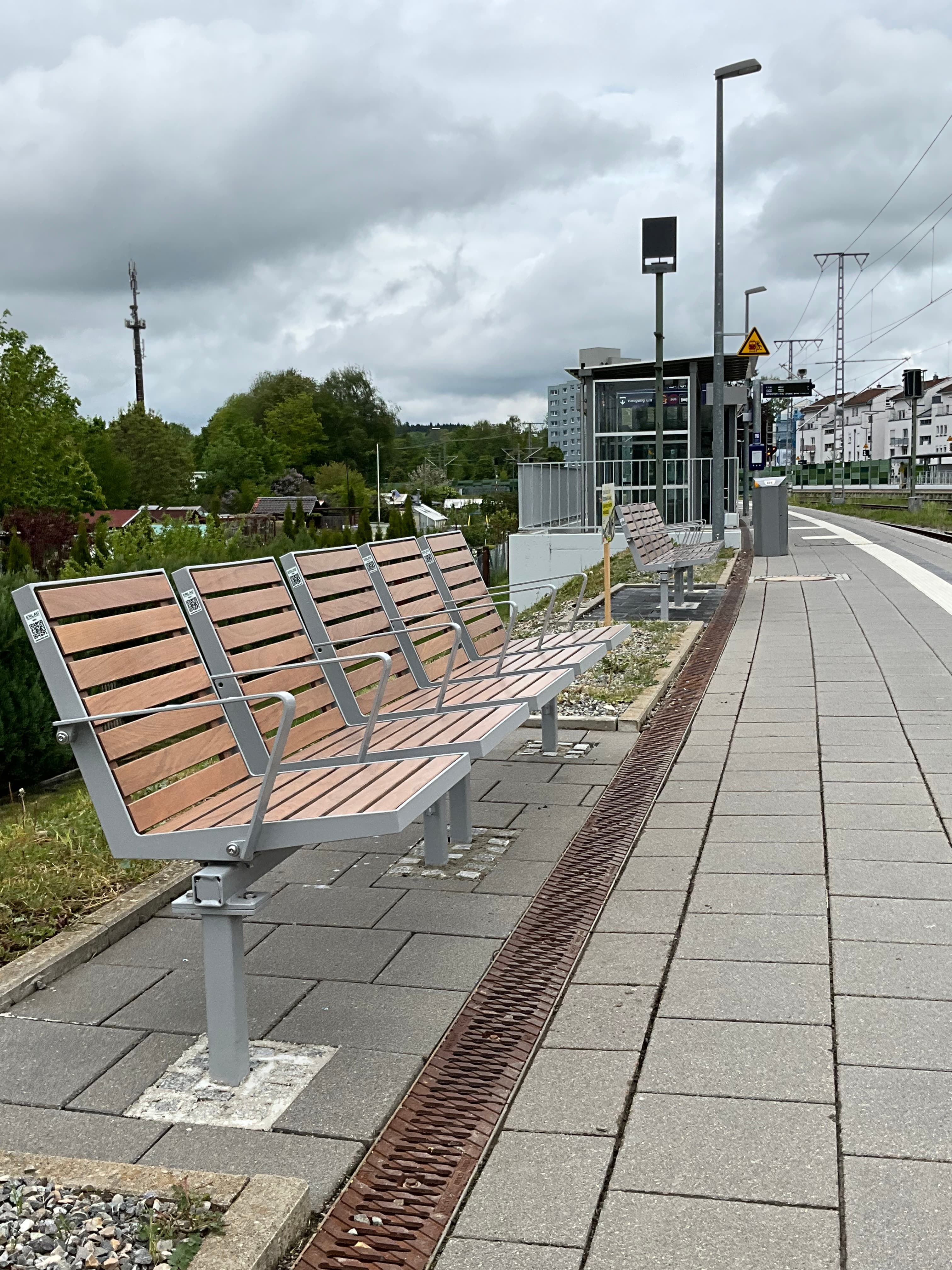 Bahnsteig des Bahnhofs Leutkirch im Allgäu mit neuen Sitzbänken aus Holzlatten.