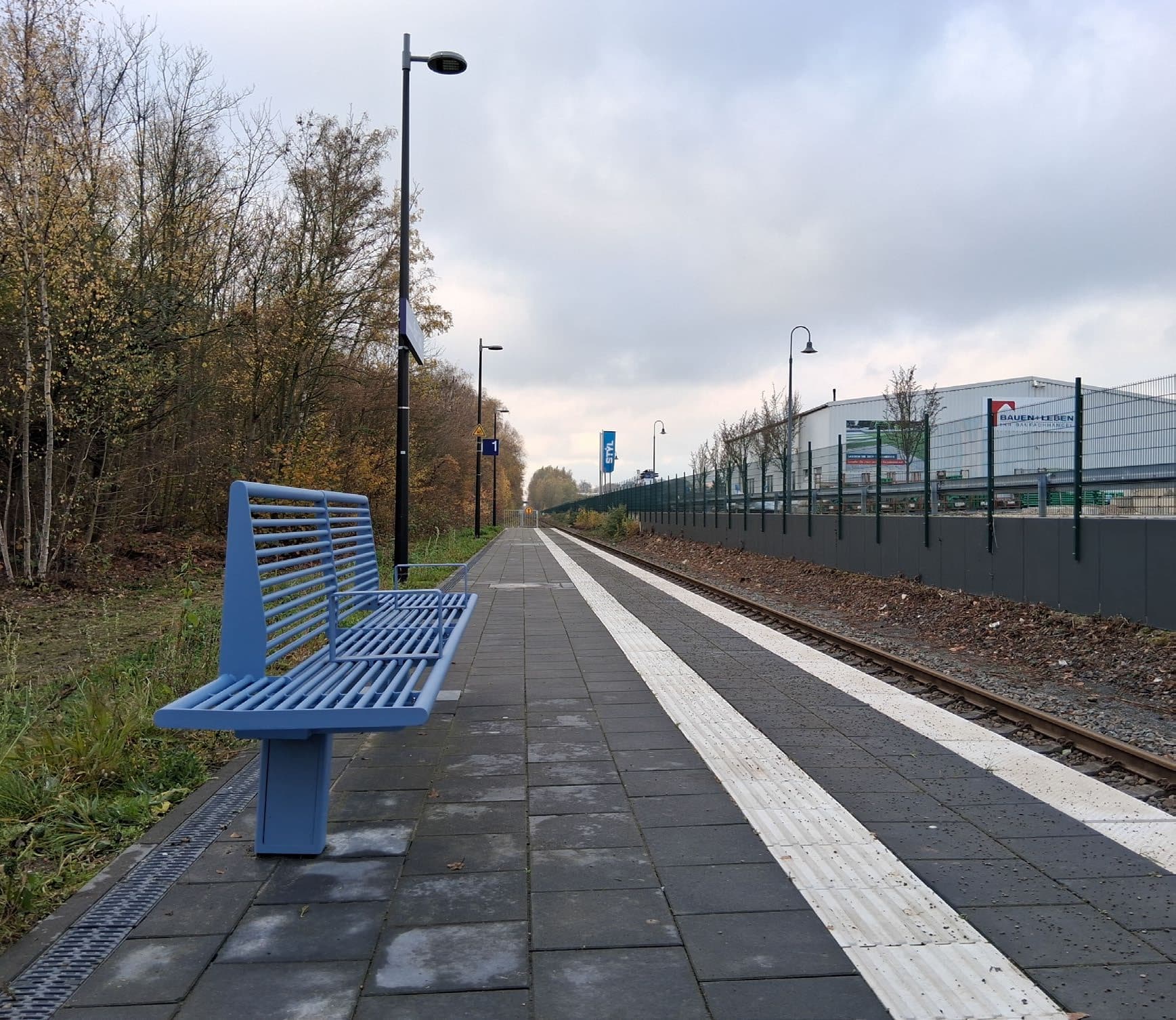 Bahnsteig mit taktilem Leitsystem und Sitzgelegenheit.