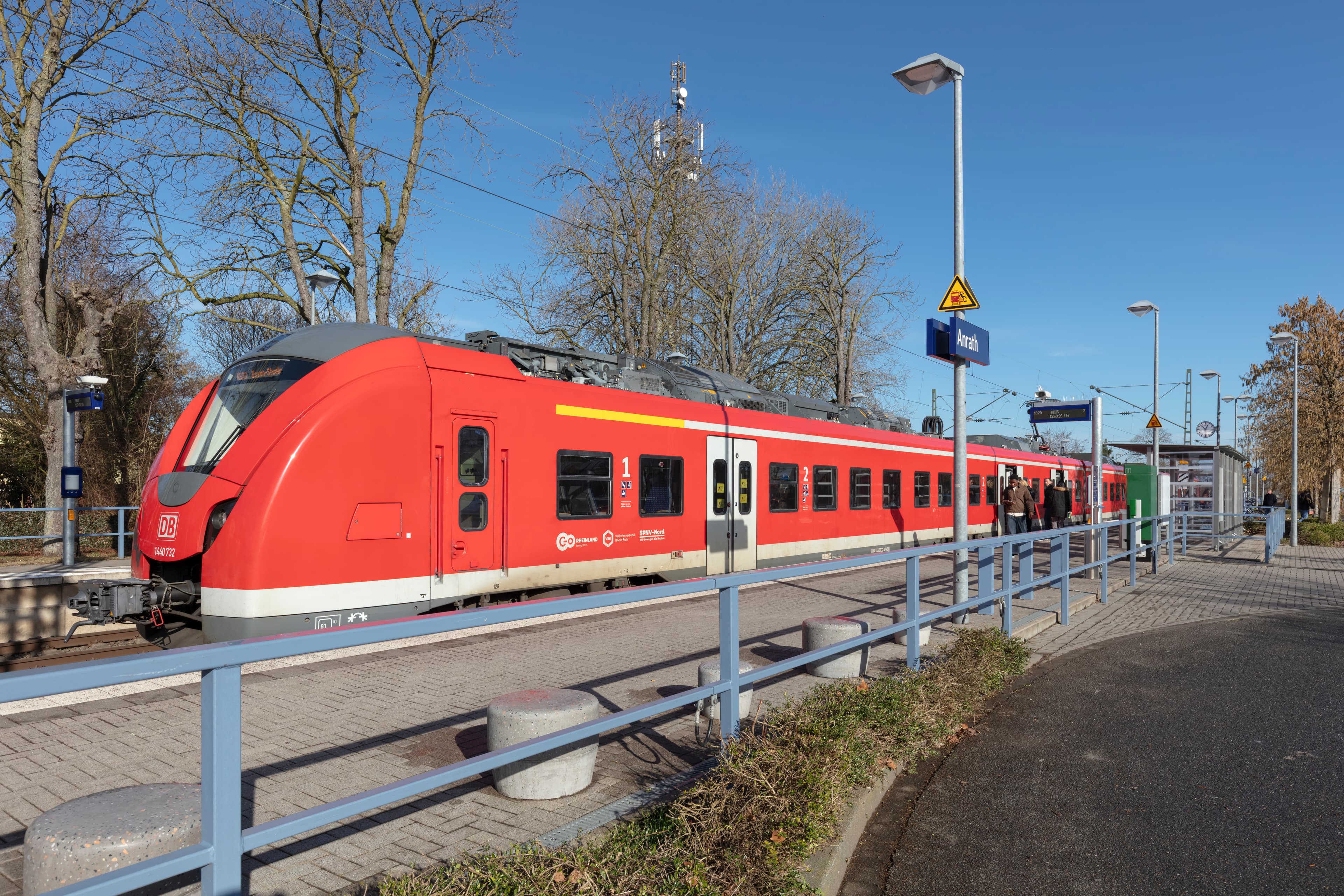 Einfahrender roter Zug an einem Bahnsteig.
