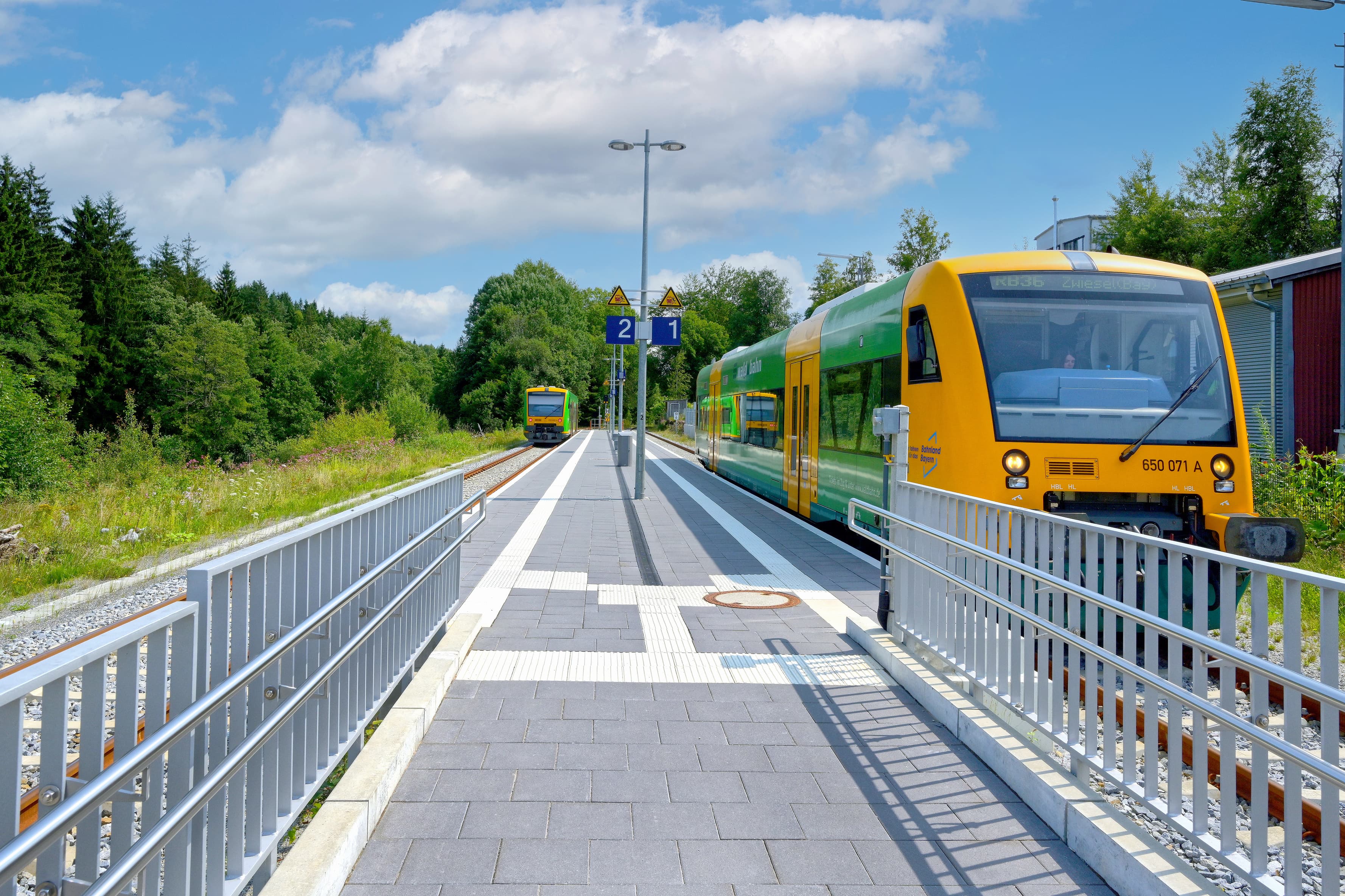 Die Zugangsrampe zum Mittelbahnsteig mit Handläufen auf beiden Seiten und dem taktilen Leitsystem inkl. Aktionsfeldern. Rechts im Bild hält ein Zug am Gleis 1.